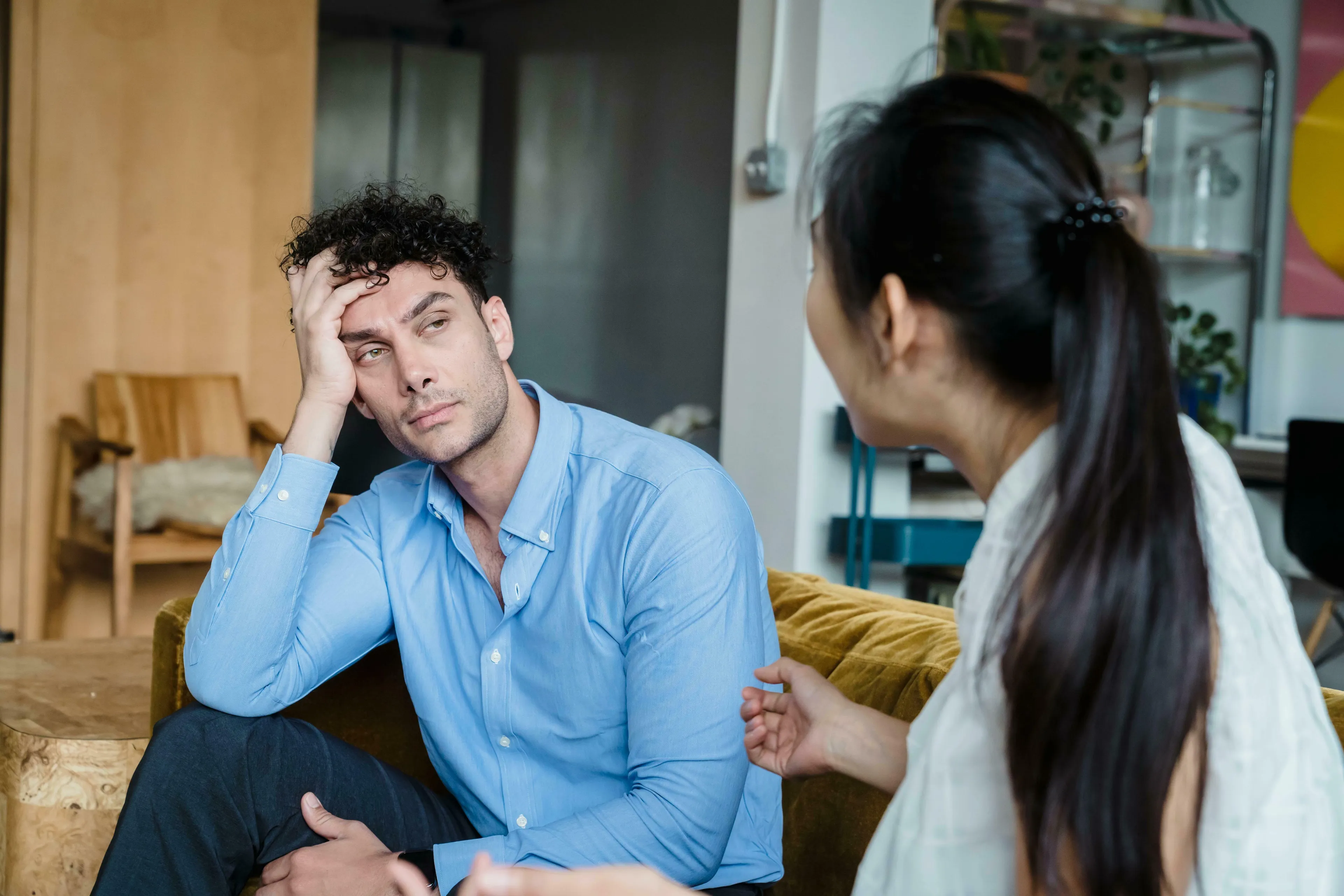 A man with curly hair and a blue shirt, looking bored during a conversation with an unseen woman. How unique are you?