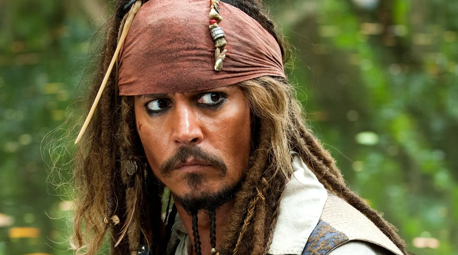 Close-up of Captain Jack Sparrow looking stern, with his signature dreadlocks, beads, and bandana.