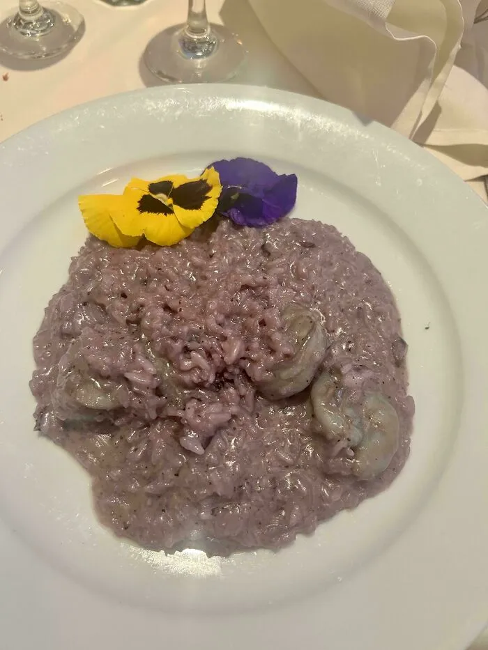 Purple risotto topped with edible yellow and purple flowers, showing questionable food combos.