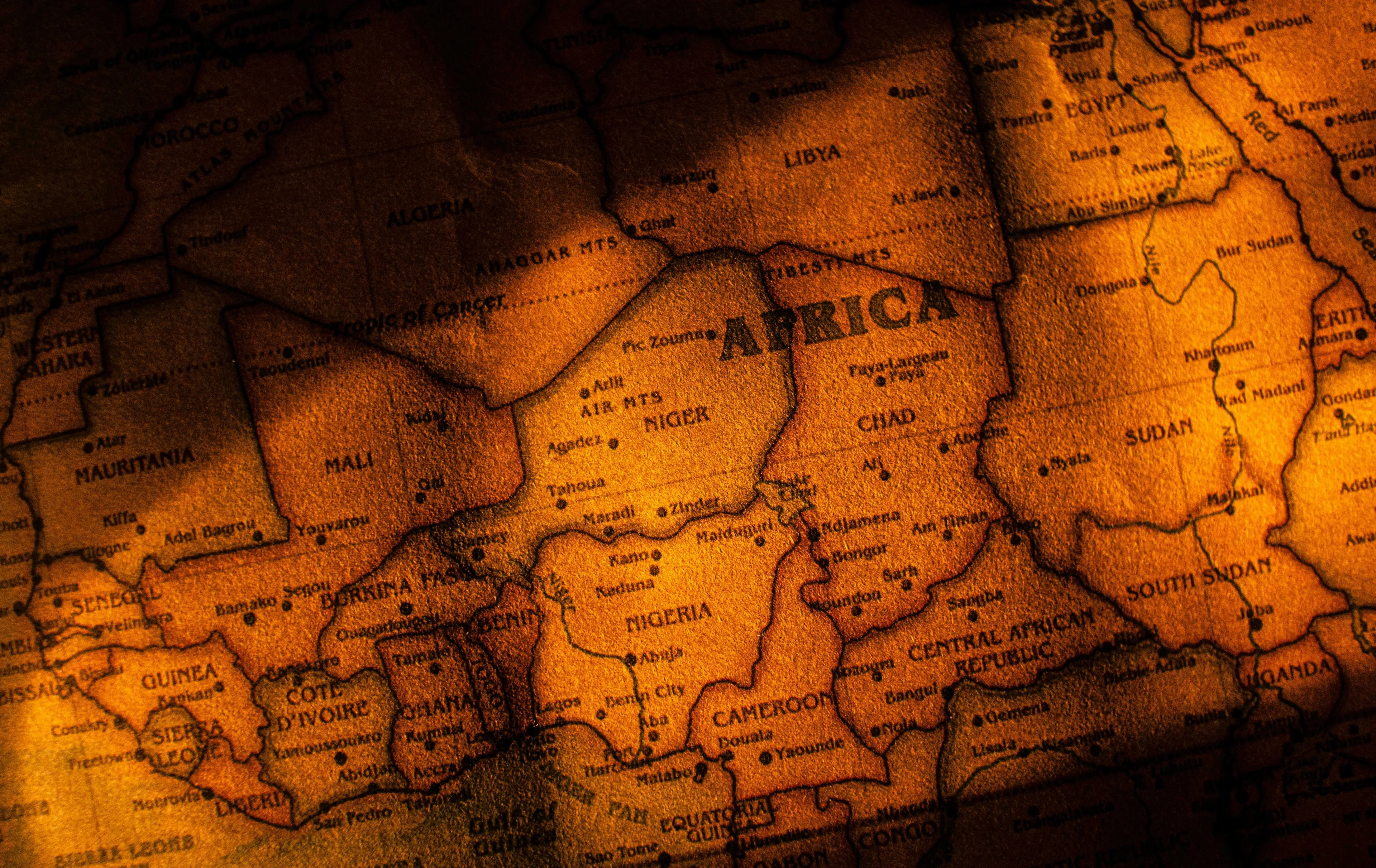 An old, textured map of Africa, lit with warm, golden hues. A Who Wants To Be A Millionaire question asks: What is the most spoken language in Africa?