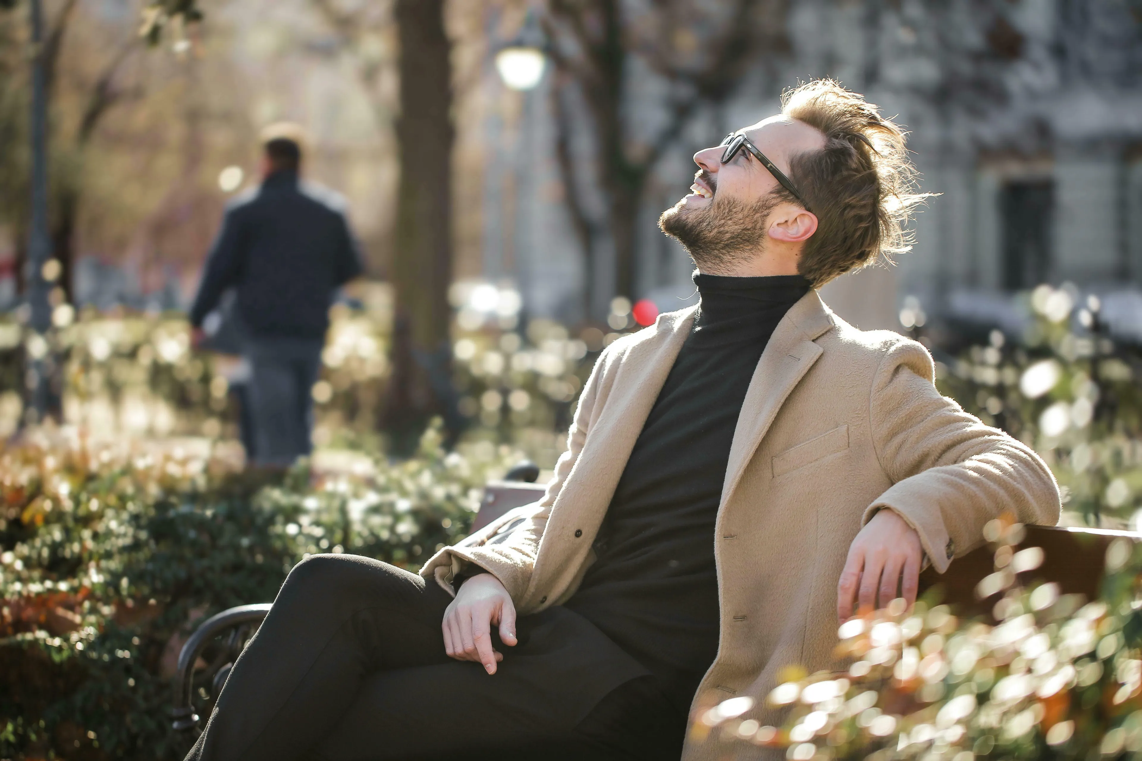 Man in sunglasses and a beige coat smiles, enjoying the sun. Reminiscent of Who Wants To Be A Millionaire? $3,000 question.