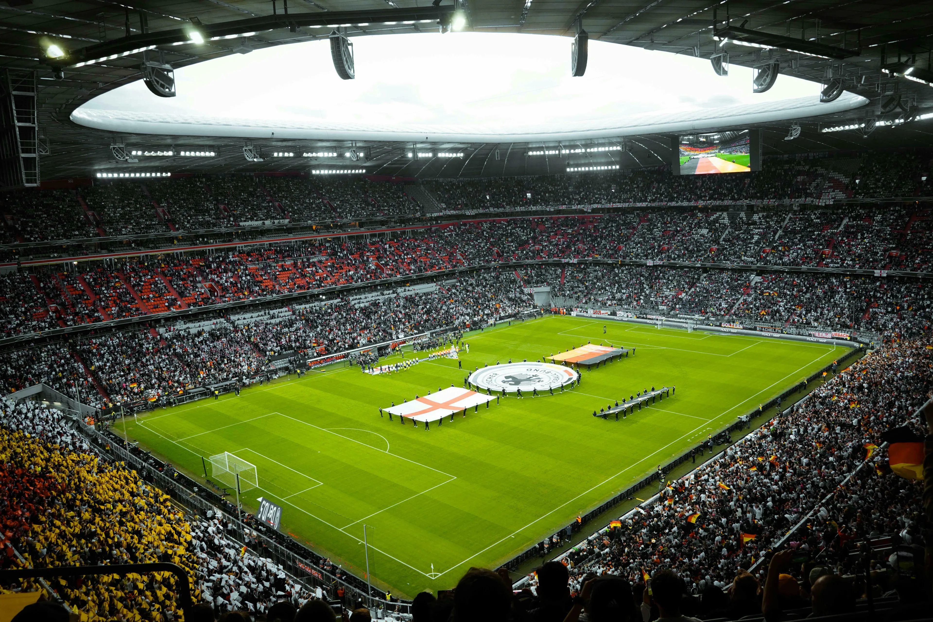 A large stadium packed with fans, flags on the field, representing countries for a FIFA World Cup game.