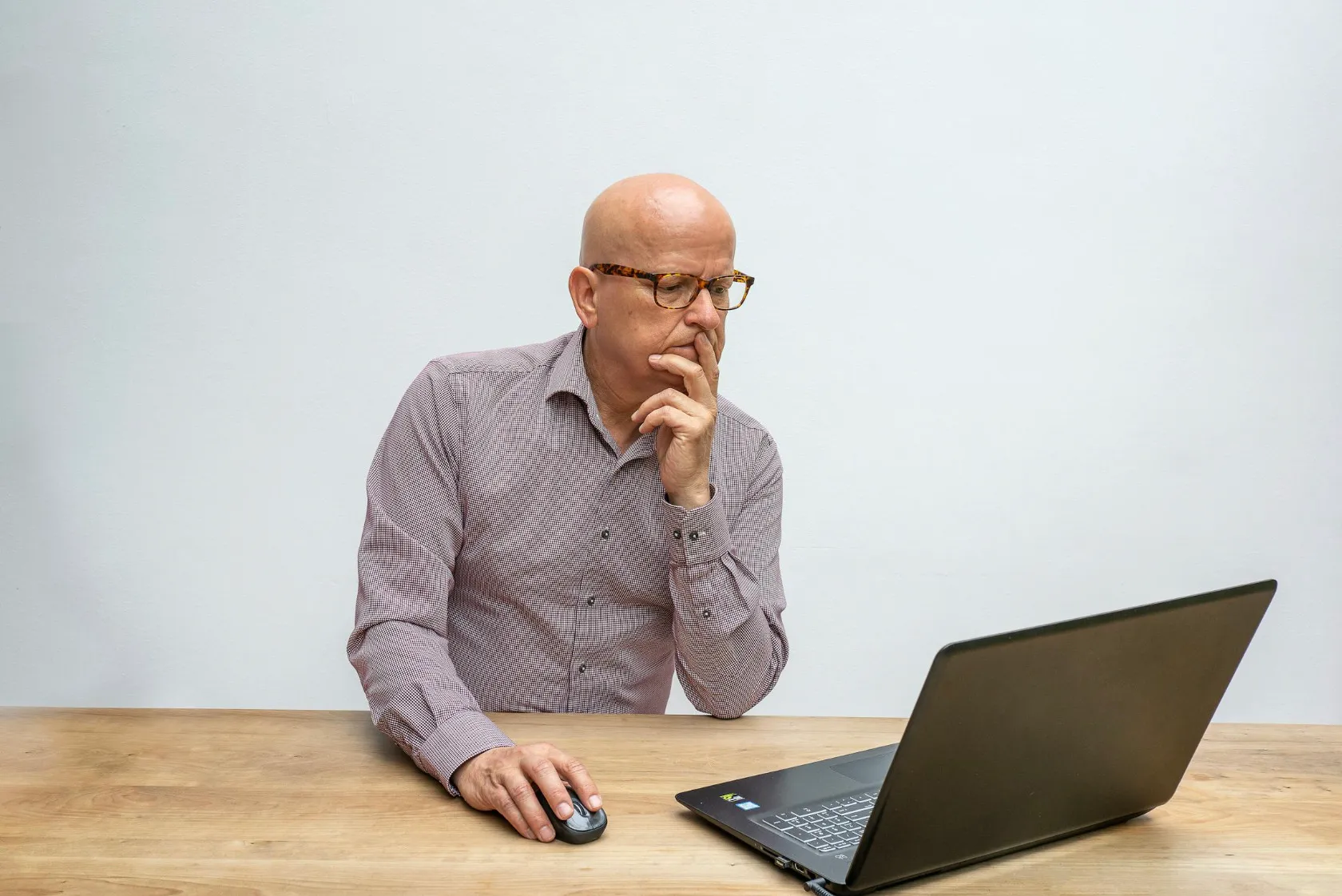 A man in glasses looks thoughtfully at a laptop while pondering Who Wants To Be A Millionaire? questions.
