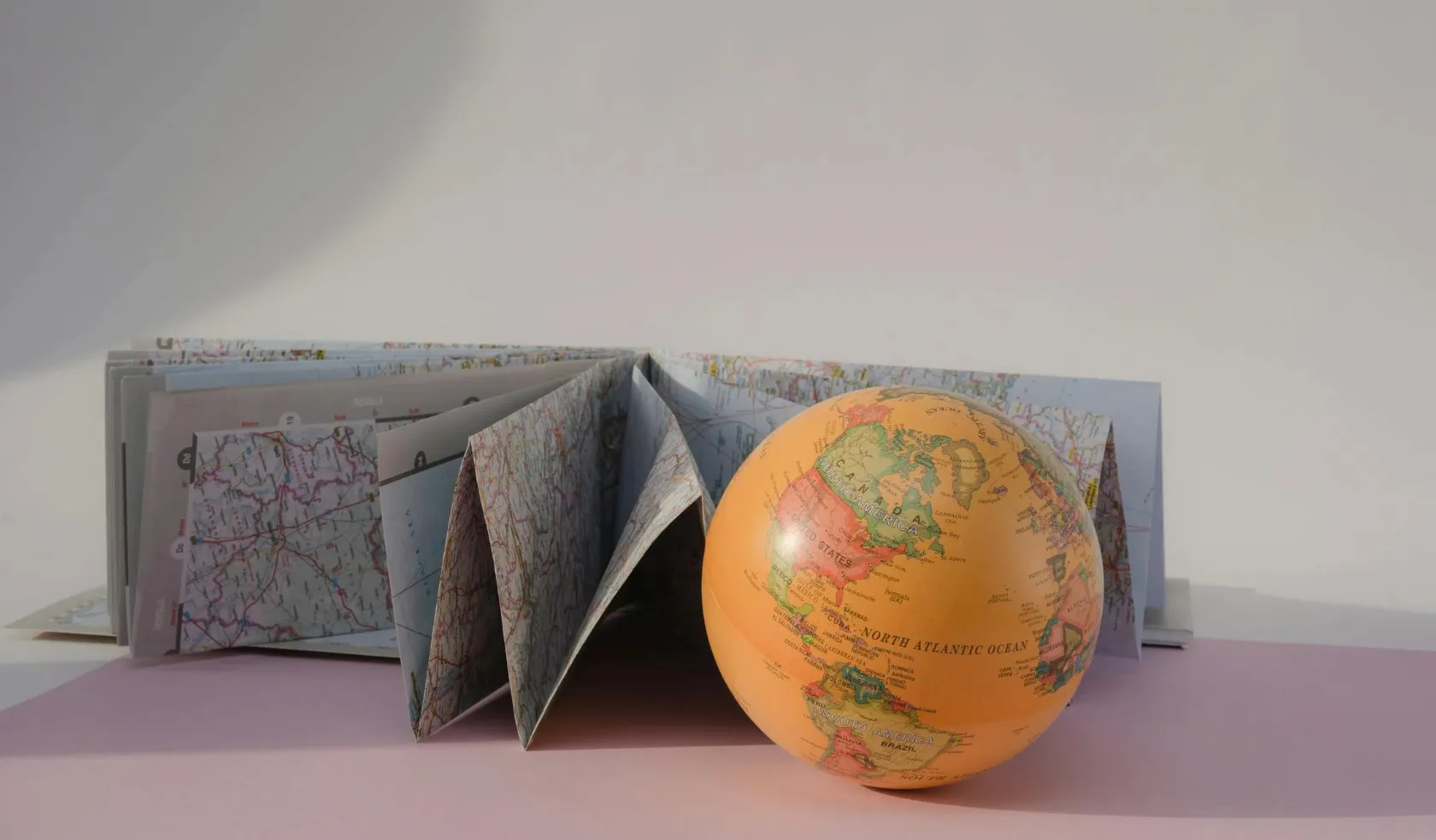 A small globe sits beside a fanned-out map. This relates to the Who Wants to Be a Millionaire question about countries never colonized by a European power.