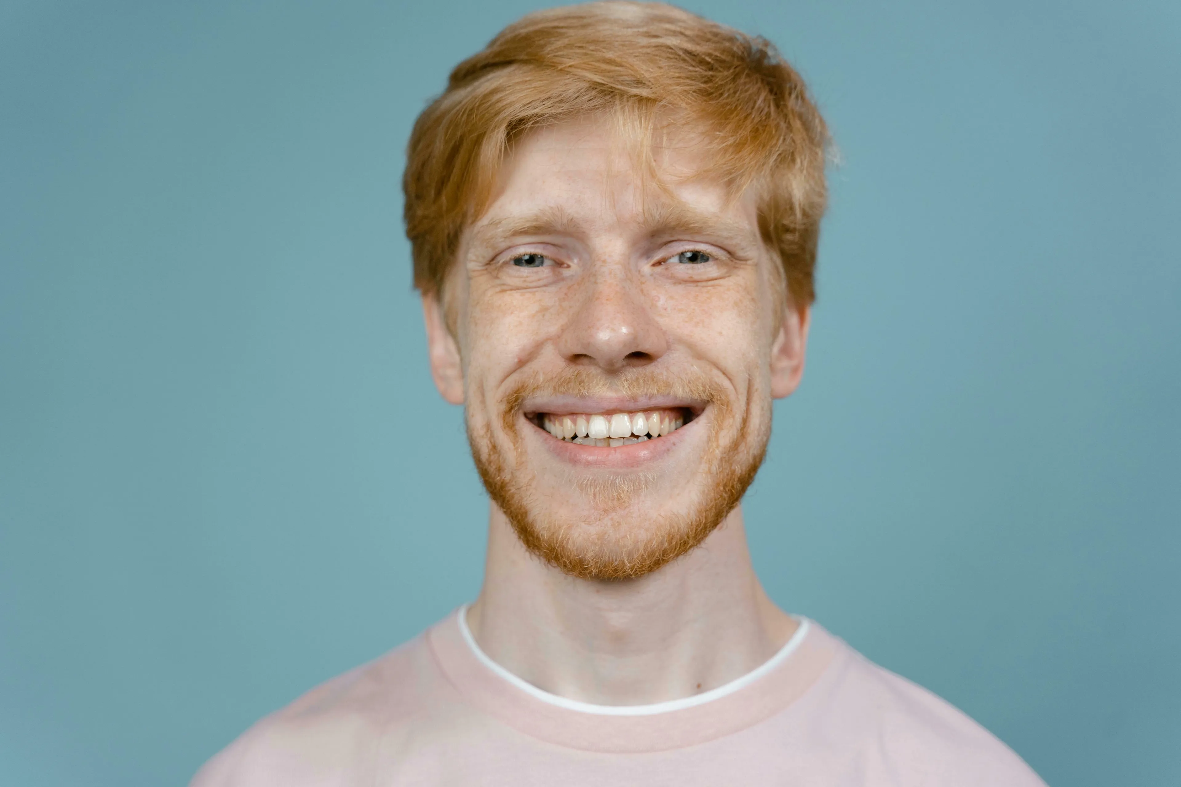 A smiling red-haired man, against a blue background, representing a general knowledge quiz question about human teeth.