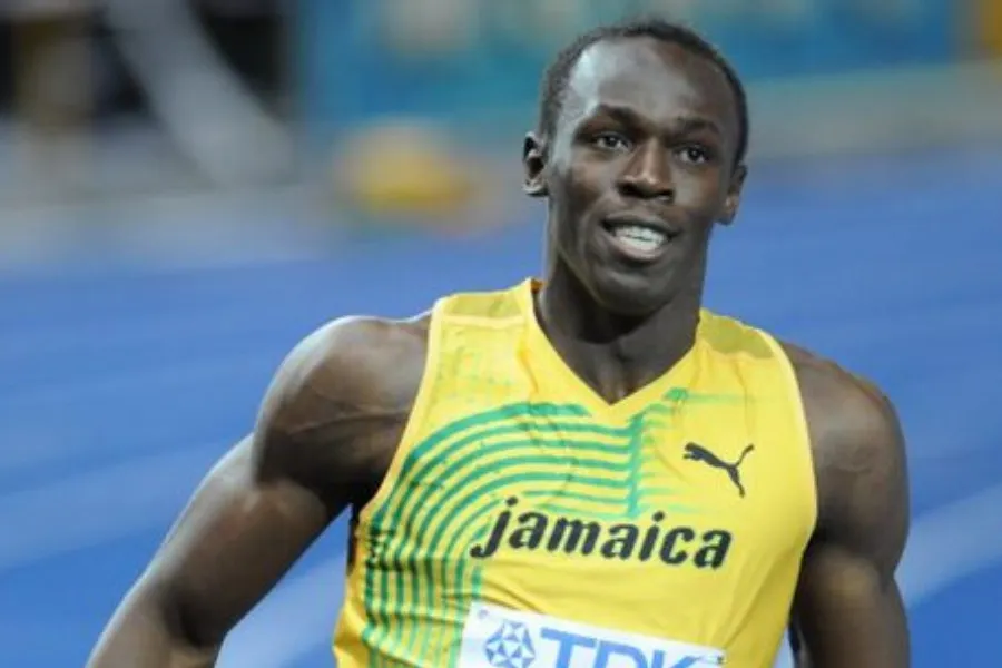 Usain Bolt, the fastest man in the world, in a yellow Jamaica track uniform, smiling slightly on a blue track.
