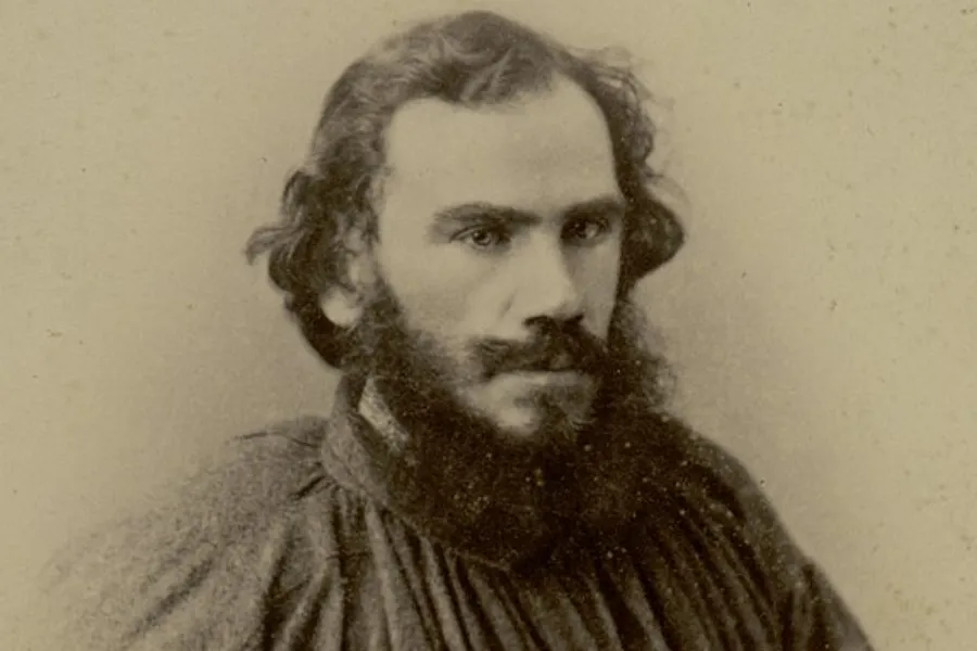 A sepia-toned portrait of Leo Tolstoy, a Russian novelist, with thick dark hair and a long beard, who wrote War and Peace.