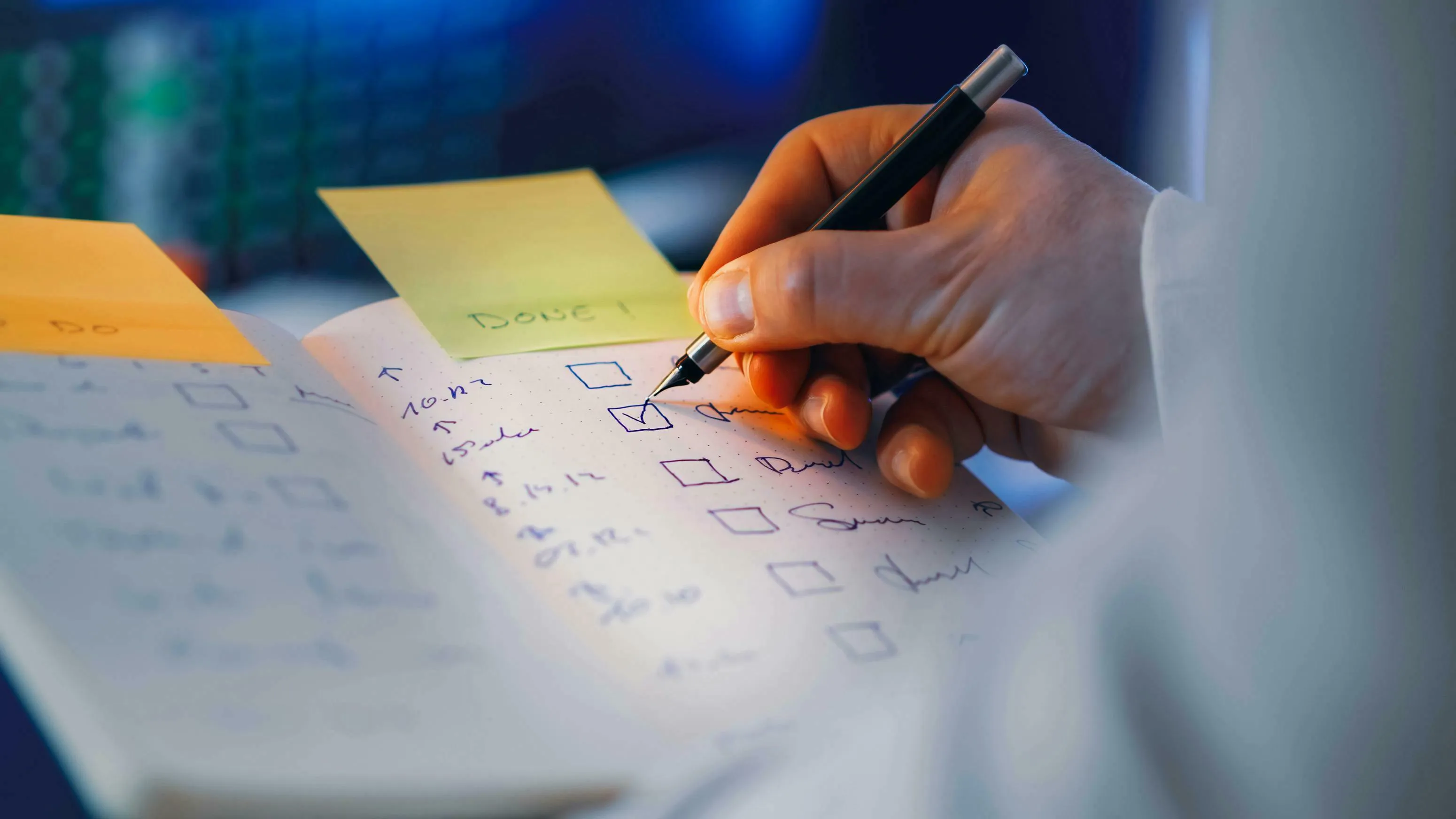 A person's hand checking a done item on a to-do list in a notebook. Shows proactive habit for procrastination type.