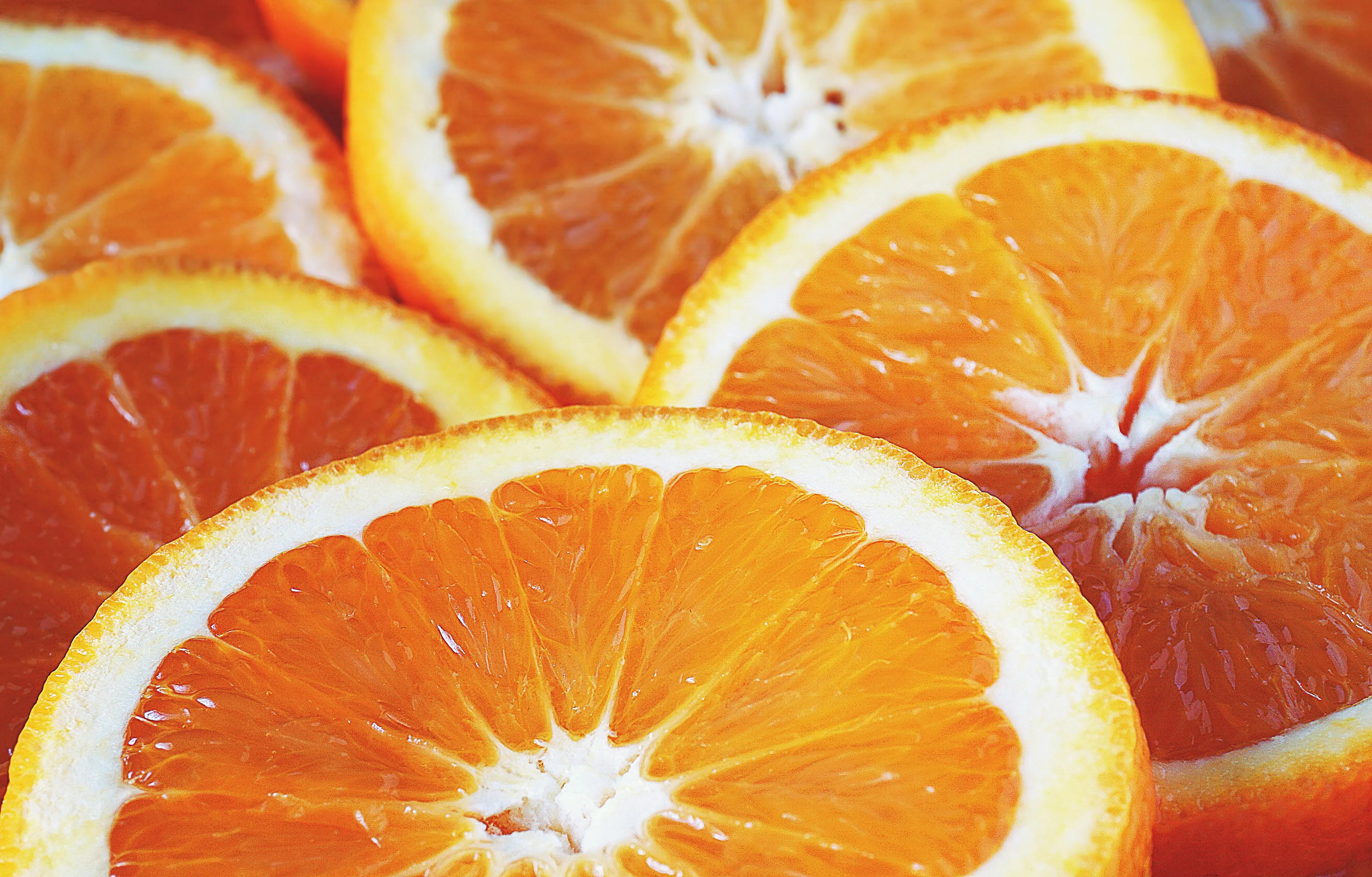 A close-up shot of several bright orange slices, a refreshing snack that matches your working style.