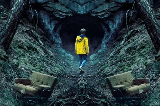 A figure in a yellow jacket walks towards a cave entrance, surrounded by dark, dense woods, like from the TV show Dark.