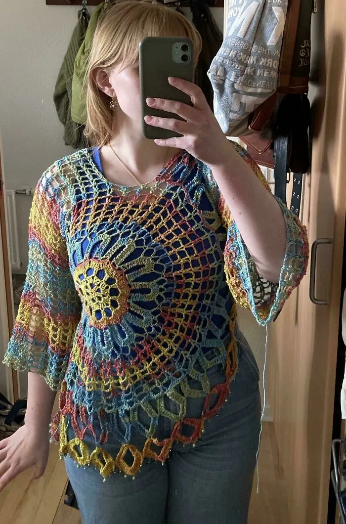 Colorful crocheted top with circular pattern worn by woman taking mirror selfie