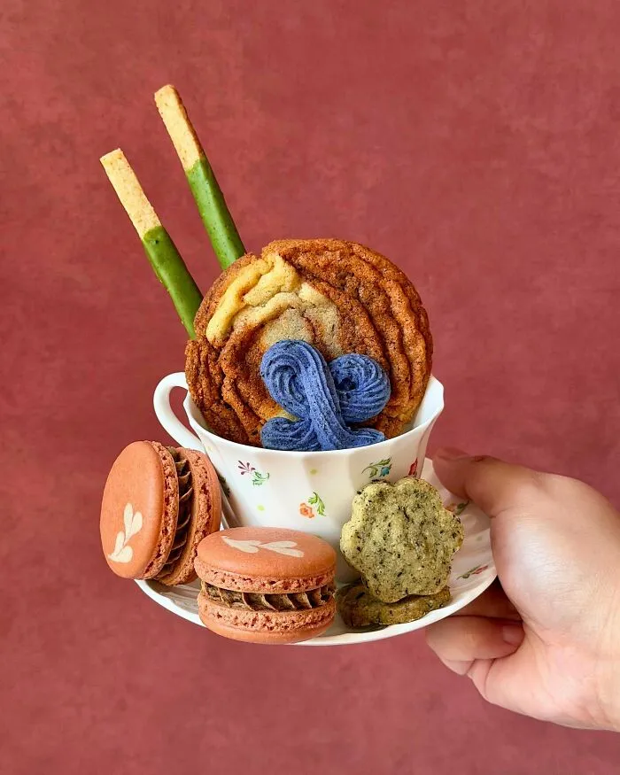 Assorted cookies and macarons arranged in teacup dessert