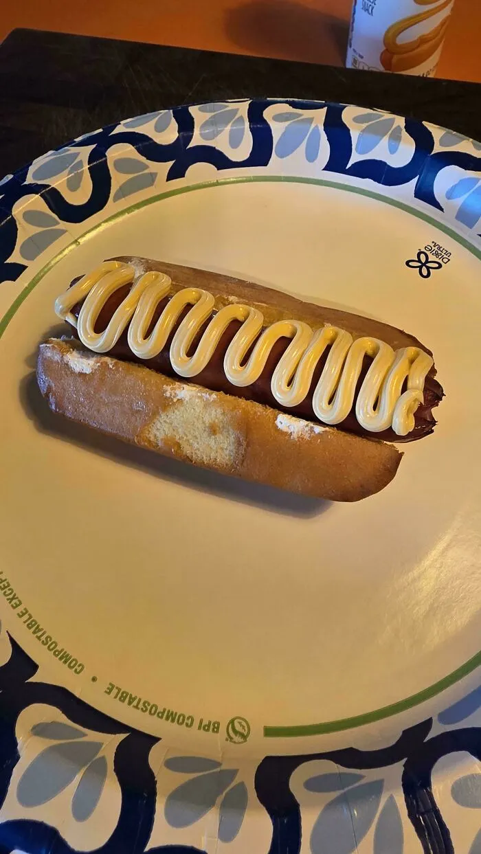 A hot dog served inside an eclairs pastry with mustard, highlighting questionable food combos.