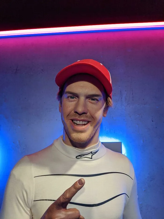 Celebrity wax figure wearing red cap and white shirt with blue lighting