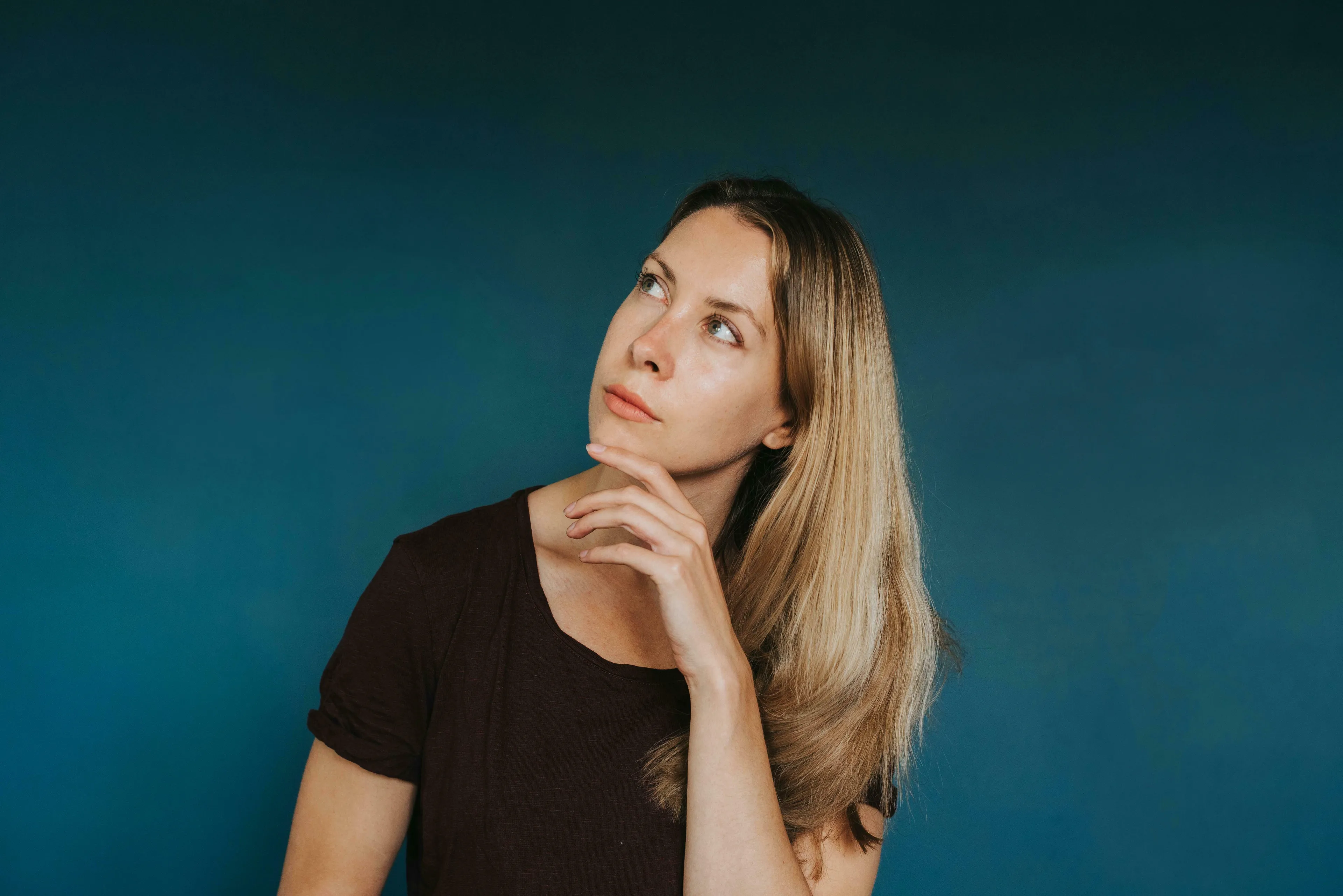 A thoughtful blonde woman in a brown shirt, hand on chin, pondering a General Knowledge Quiz question about Michael Jordan and basketball.