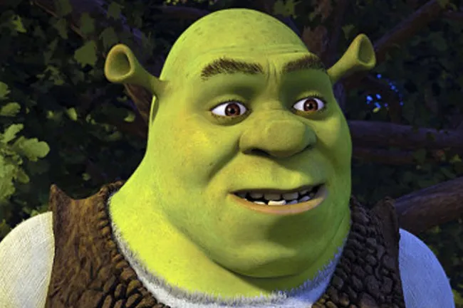 A close-up of Shrek smiling, with his green skin, brown eyes, and distinctive ear horns visible.