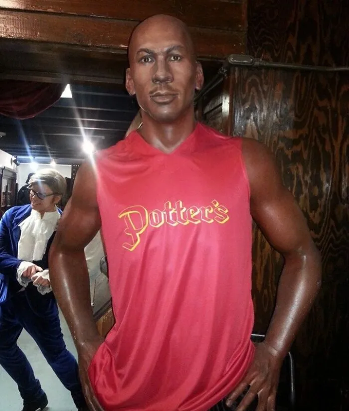Dark-skinned male celebrity wax figure wearing a red Potter's shirt