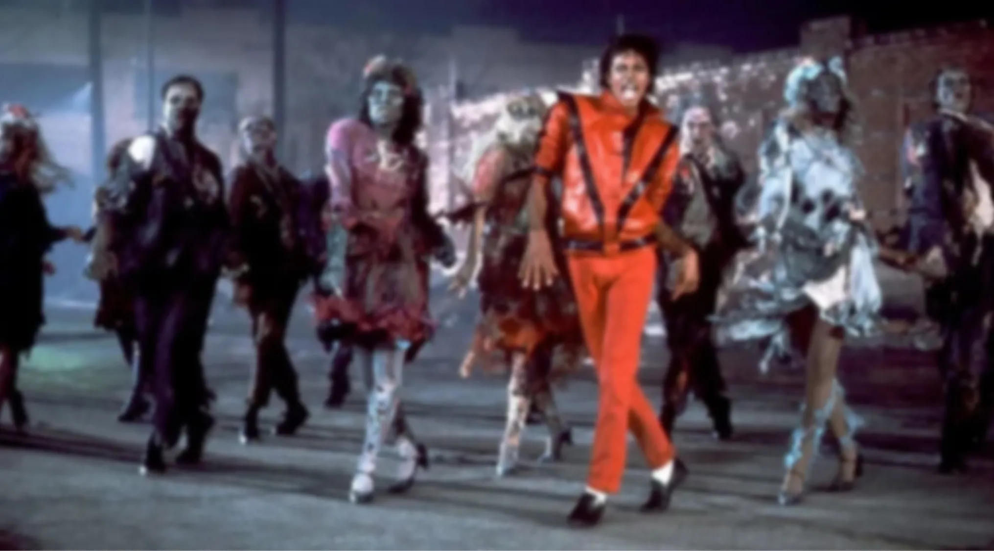 A blurry image of Michael Jackson in a red jacket dancing with zombies. Guess the blurred music video!