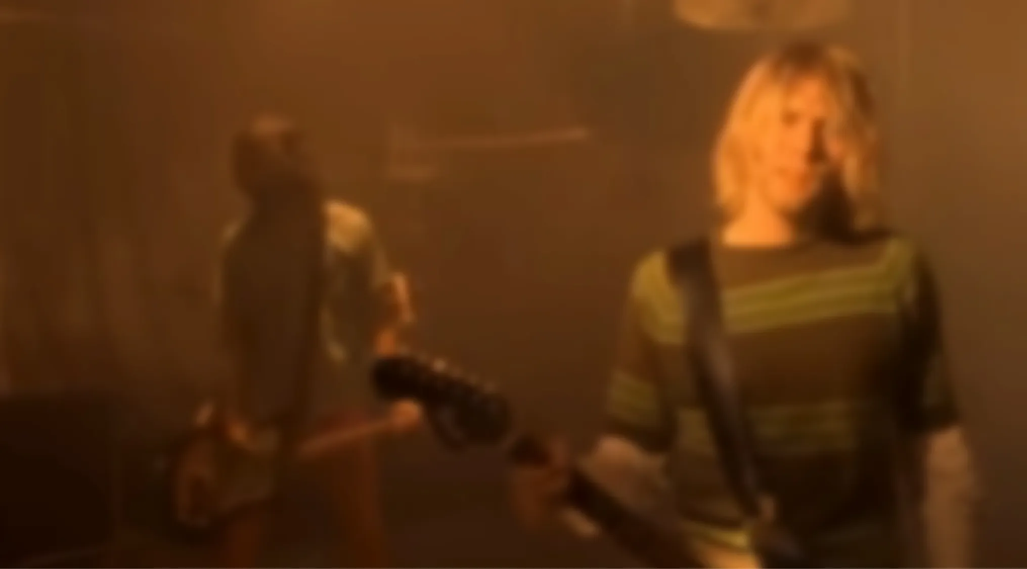A blurry image of a band with two members and guitars in a smoky room. Blurry music videos quiz.