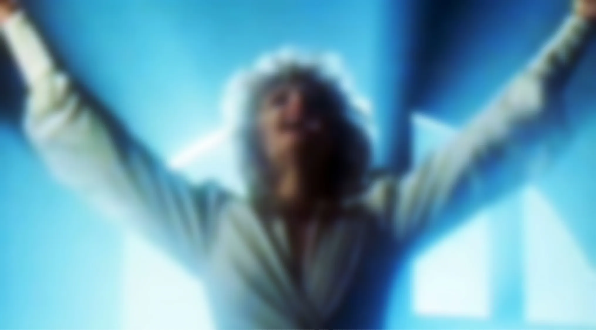 Blurry image of a person with arms raised, bathed in blue light. Can you guess this music video?