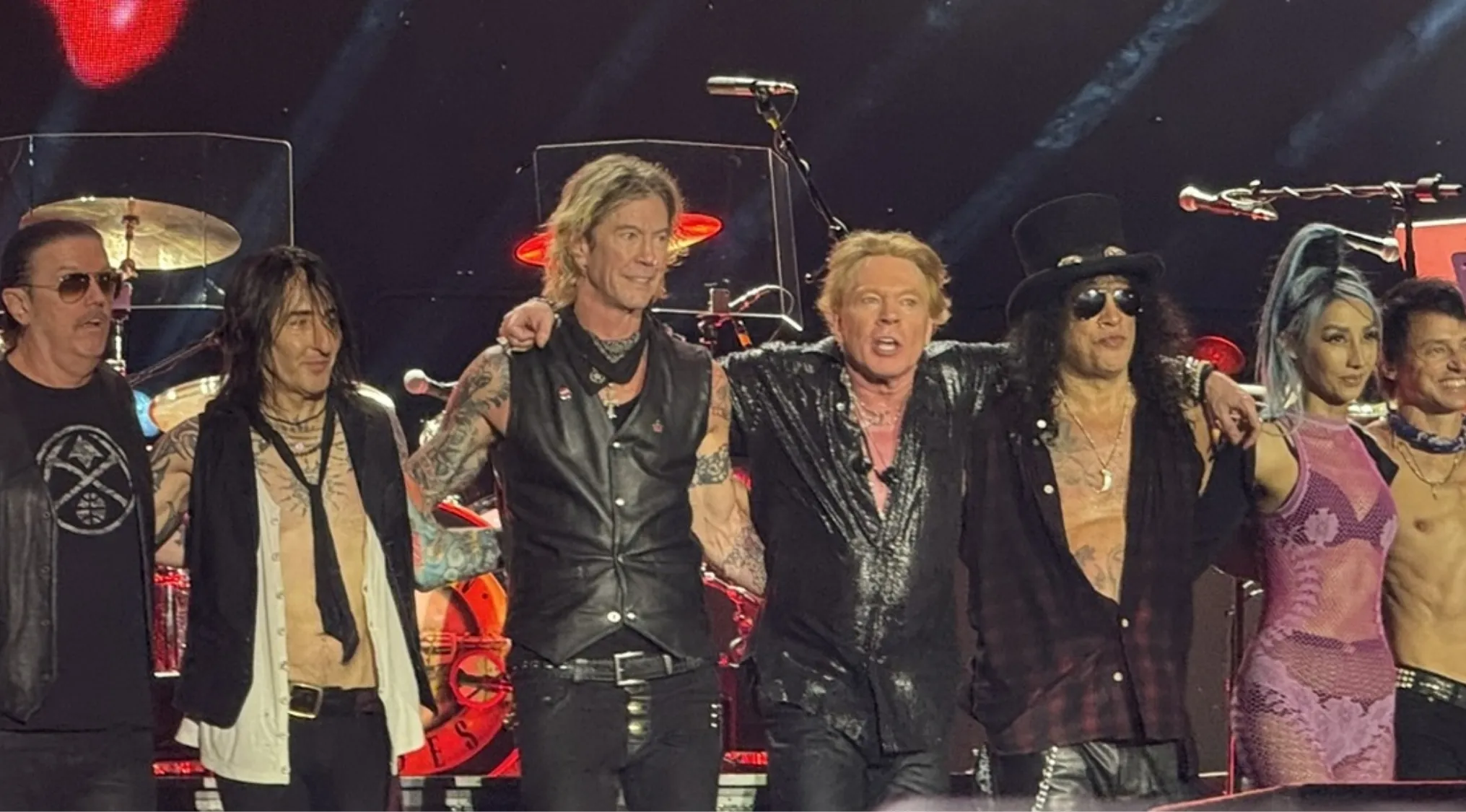 Guns N' Roses band members on stage with other performers, posing for the camera at a concert, 80s pop culture.