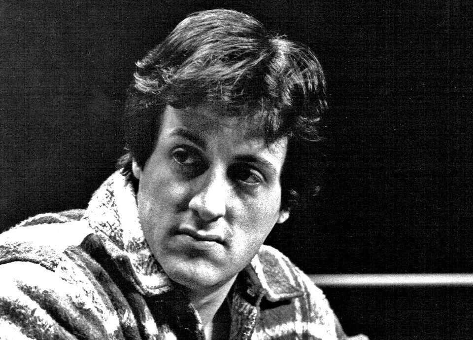 Black and white photo of young Sylvester Stallone, looking serious in a collared shirt.
