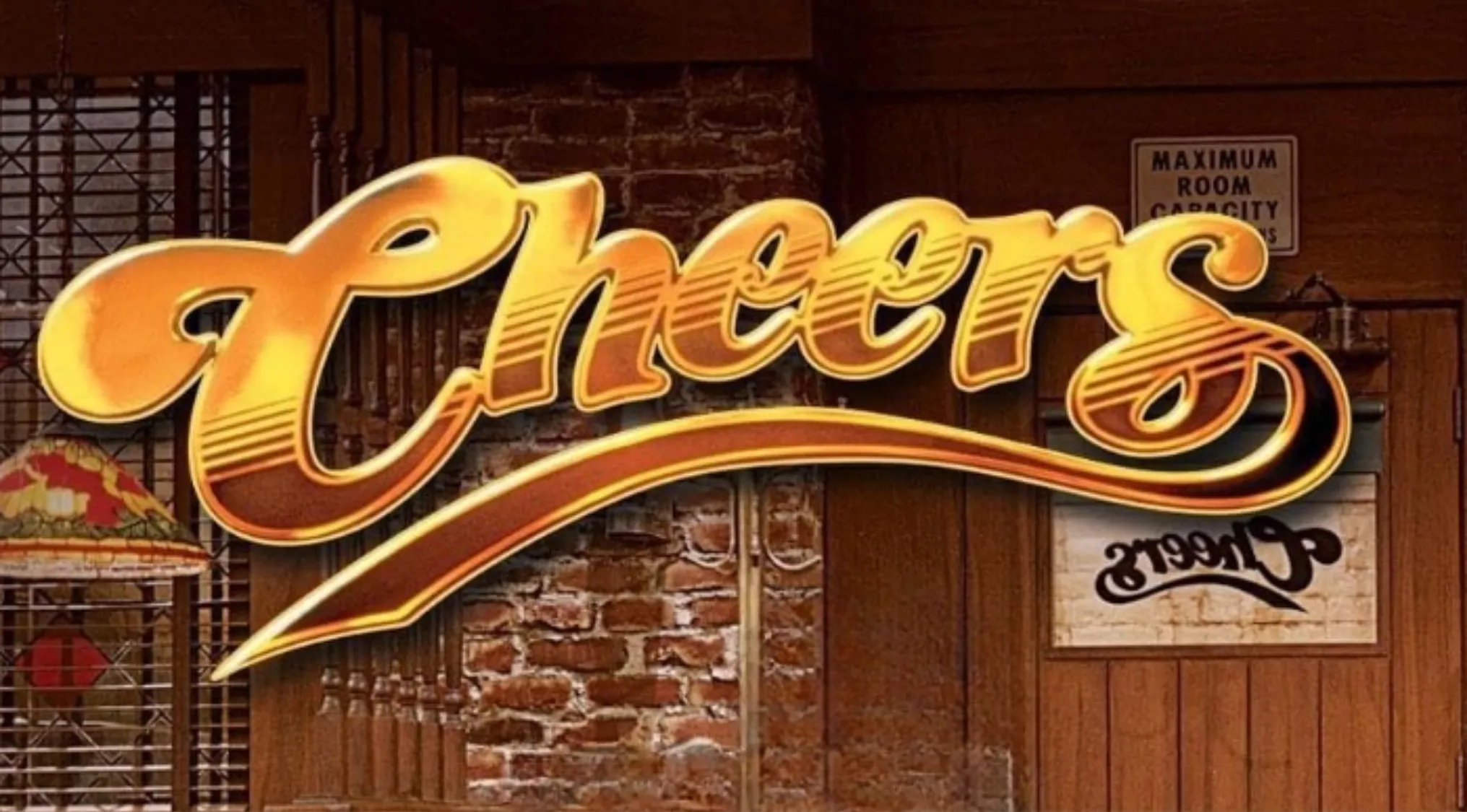The iconic Cheers logo in shiny gold letters over a brick wall and wooden door, a nod to 80s Pop Culture.