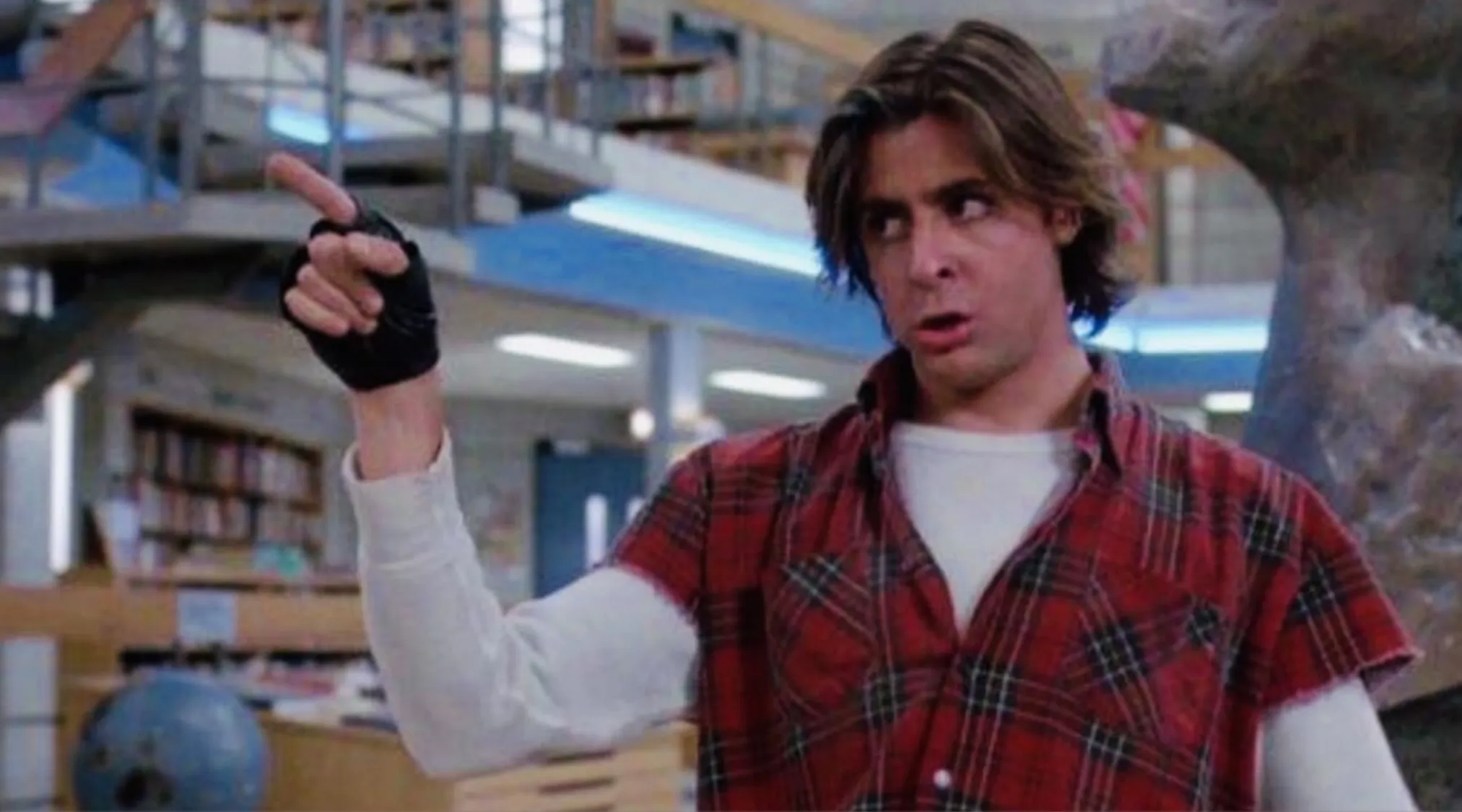 John Bender from The Breakfast Club, wearing a plaid shirt and fingerless glove, raising his middle finger, an iconic 80s pop culture image.