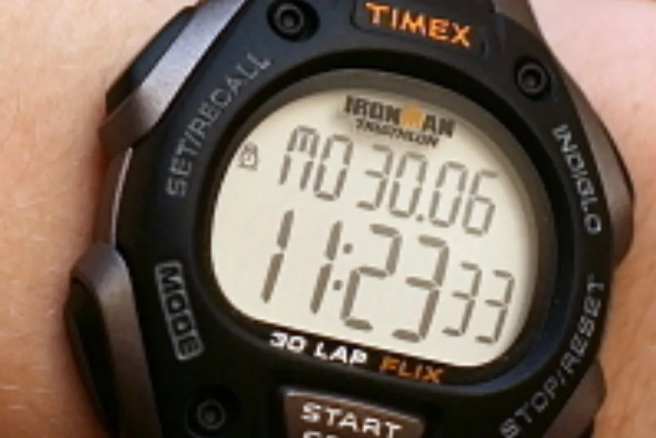 Close-up of a Timex Ironman digital watch, displaying time and date on its LCD screen.