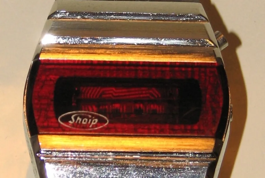 Close-up of a vintage Sharp digital watch with a red LCD screen, popular for its multifunctional features.