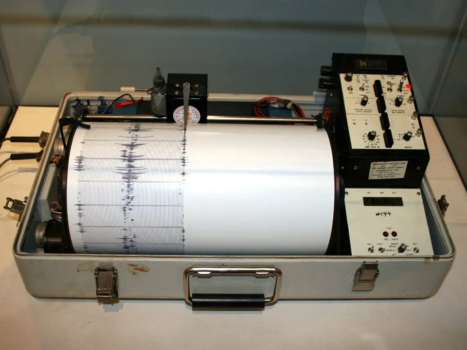 A seismograph in a case with a paper roll displaying seismic activity. Test your science general knowledge.