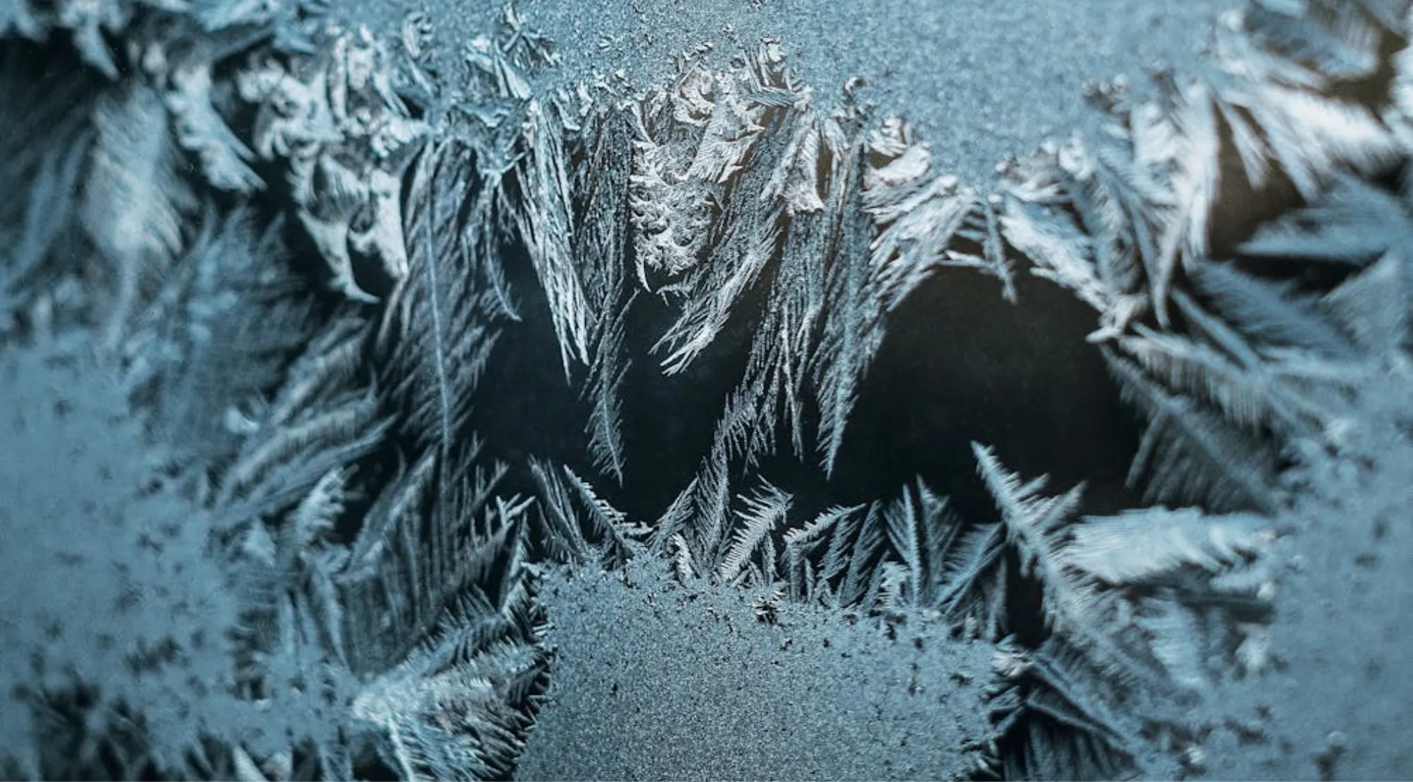 Close-up of intricate frost patterns on a window, highlighting the beauty of winter. Learn about First Aid for frostbite.