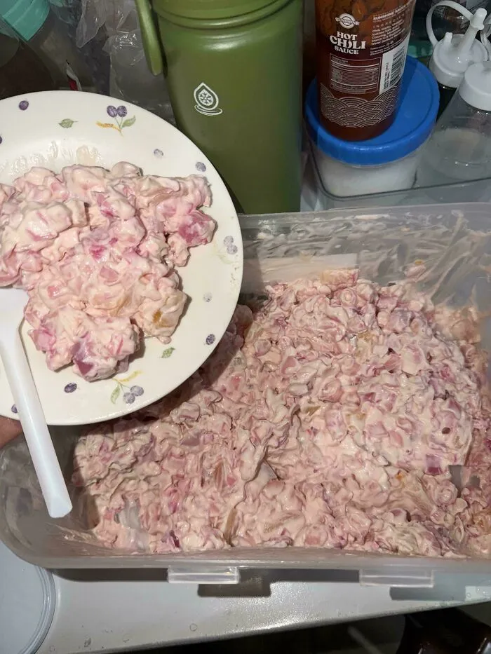 A large tub and plate filled with a pink creamy salad, presenting questionable food combos.