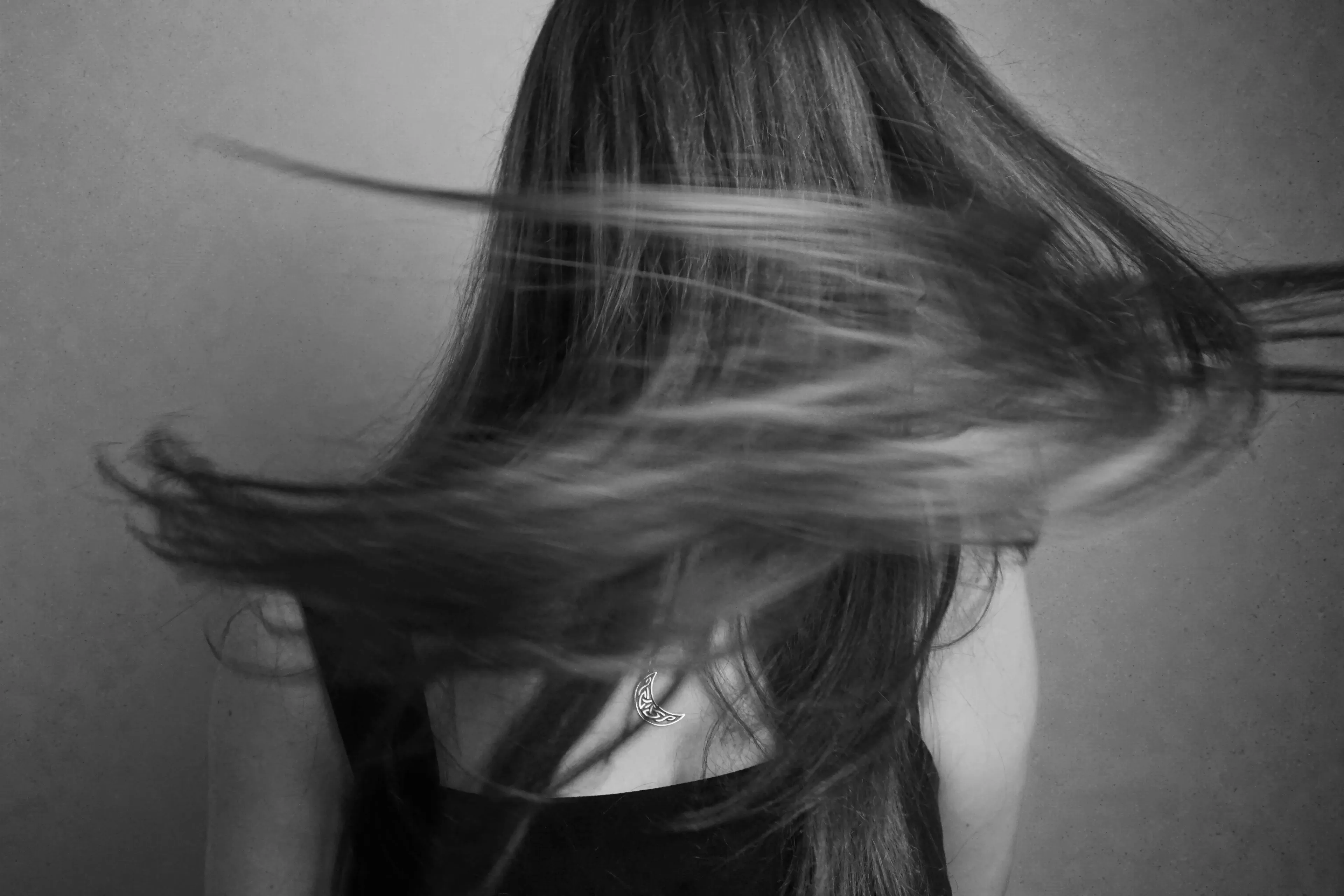 Black and white image of a woman with long hair flowing to the left, showing her back and a moon necklace. British Vocabulary Quiz.