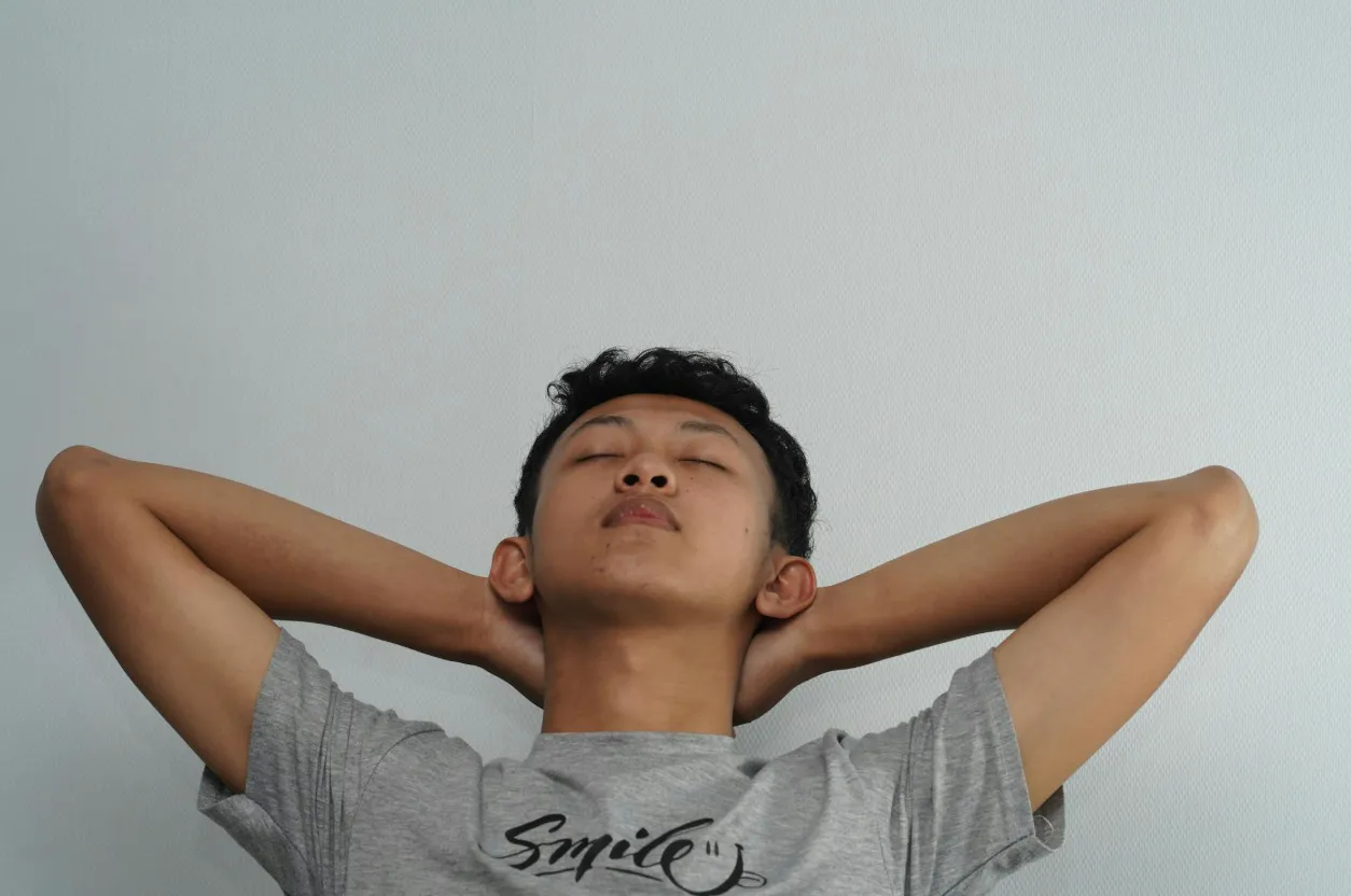 A man with hands behind his head, eyes closed, appearing very relieved against a white background. Gutted means very relieved.