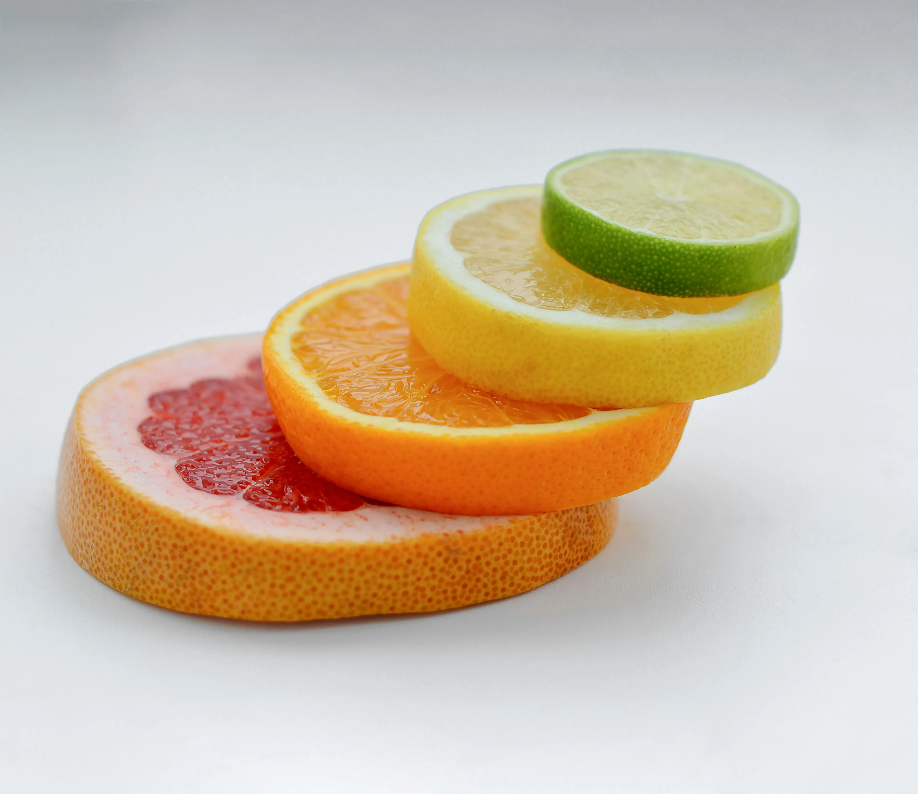 Slices of grapefruit, orange, lemon, and lime stacked, creating a vibrant display of citrus fruits. Evokes a good feeling.