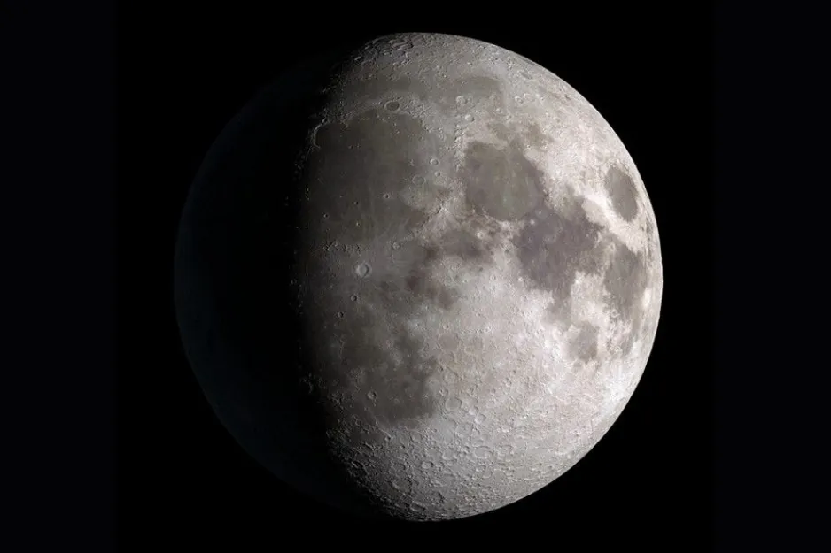 A detailed image of the moon, illuminated as a Waxing Gibbous phase against a dark, starry sky.
