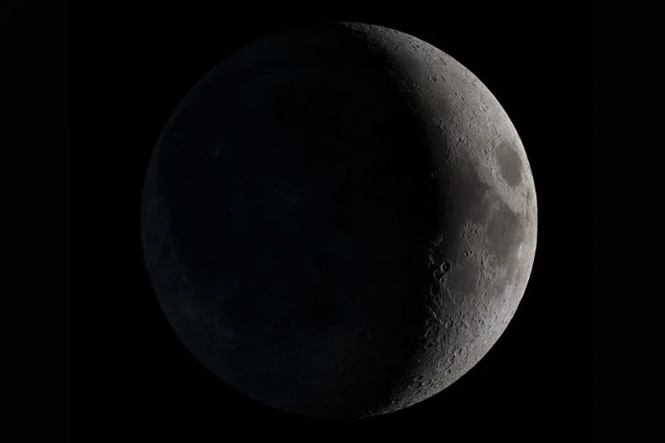 A detailed close-up of the Moon, showcasing a Waxing Crescent phase with visible craters against the dark sky.