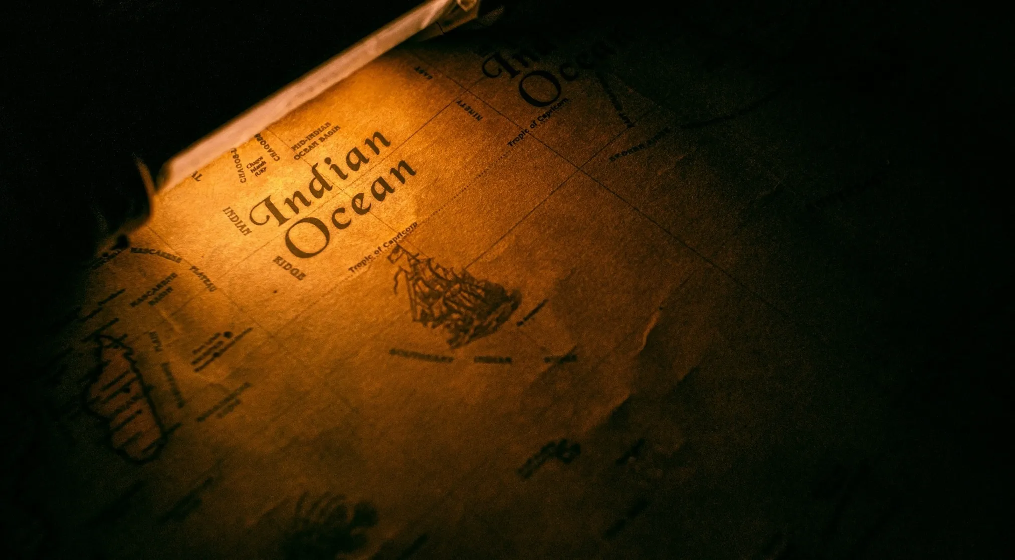 An old, illuminated map of Earth, highlighting the Indian Ocean with a ship illustration. How many oceans are on Earth?