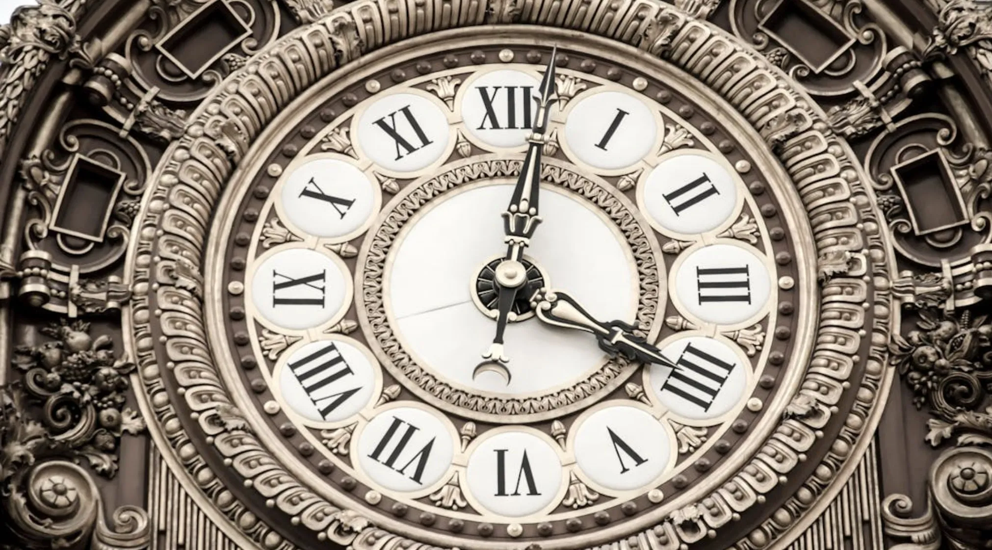 An ornate antique clock with Roman numerals on its face, showcasing intricate details. What does the letter L represent?