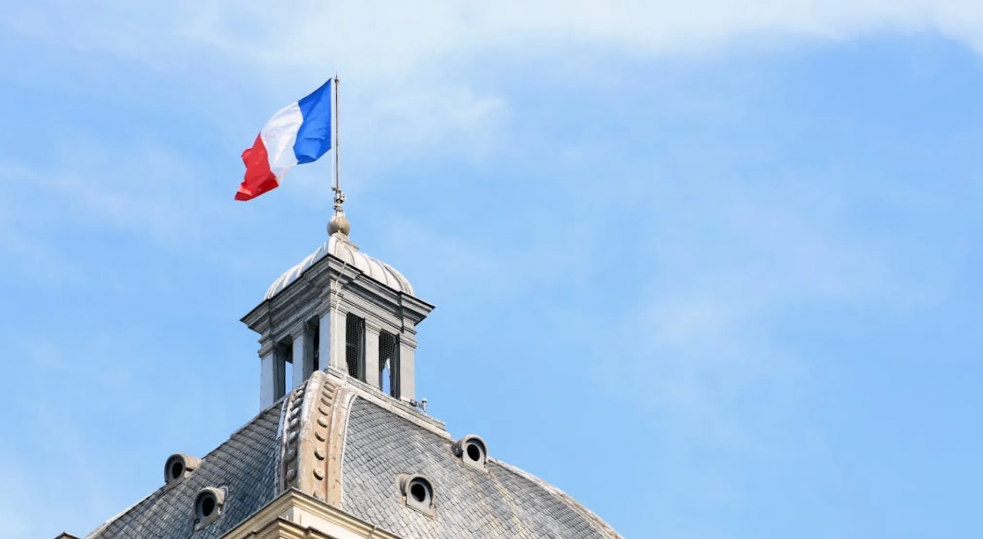 French flag flying above a historical building. How many countries share a land border with France in total?