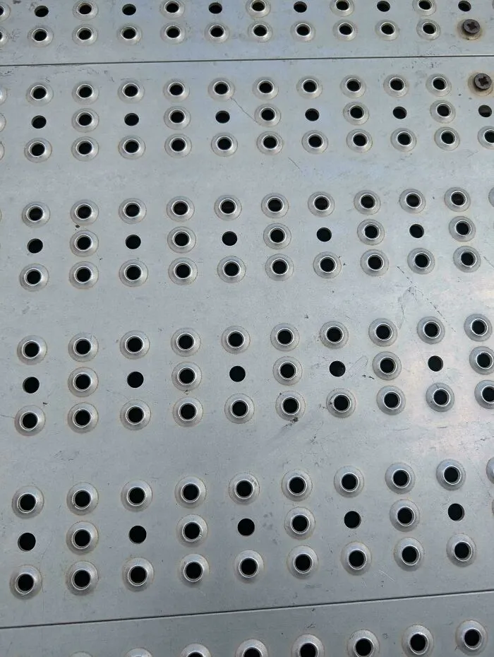 Why Does This Metal Floor Of A Carnival Ride Interior Holes With Extruding Edges, But Interior Holes That Lie Flush With The Surface? Is It Just Aesthetic? Or Does It Serve Some Purpose For Drainage, Traction Or Otherwise?