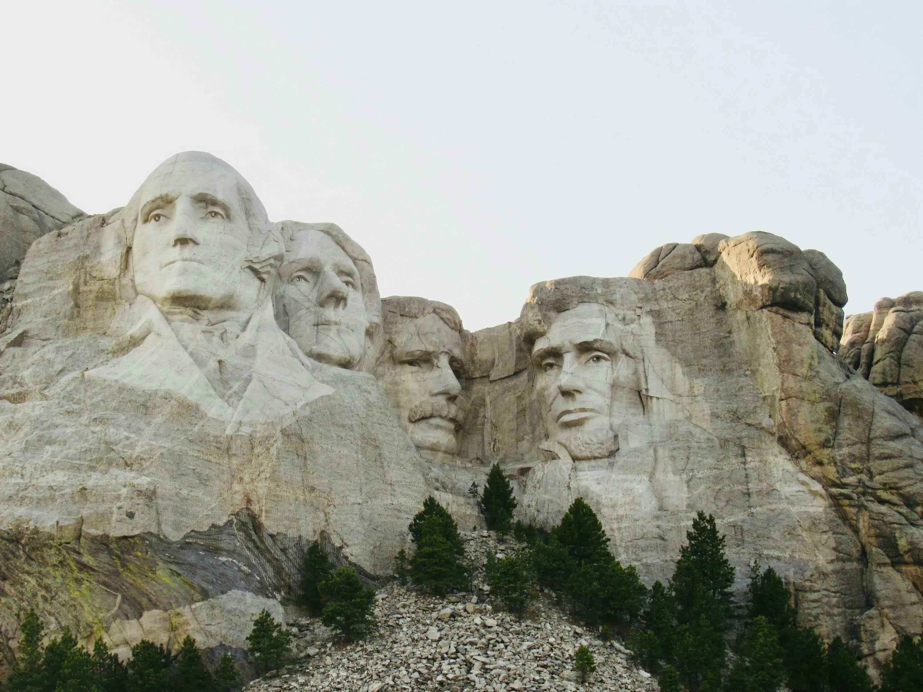 Mount Rushmore carvings, featuring four US presidents on a rock face, with trees below, for a US State Capitals Quiz.
