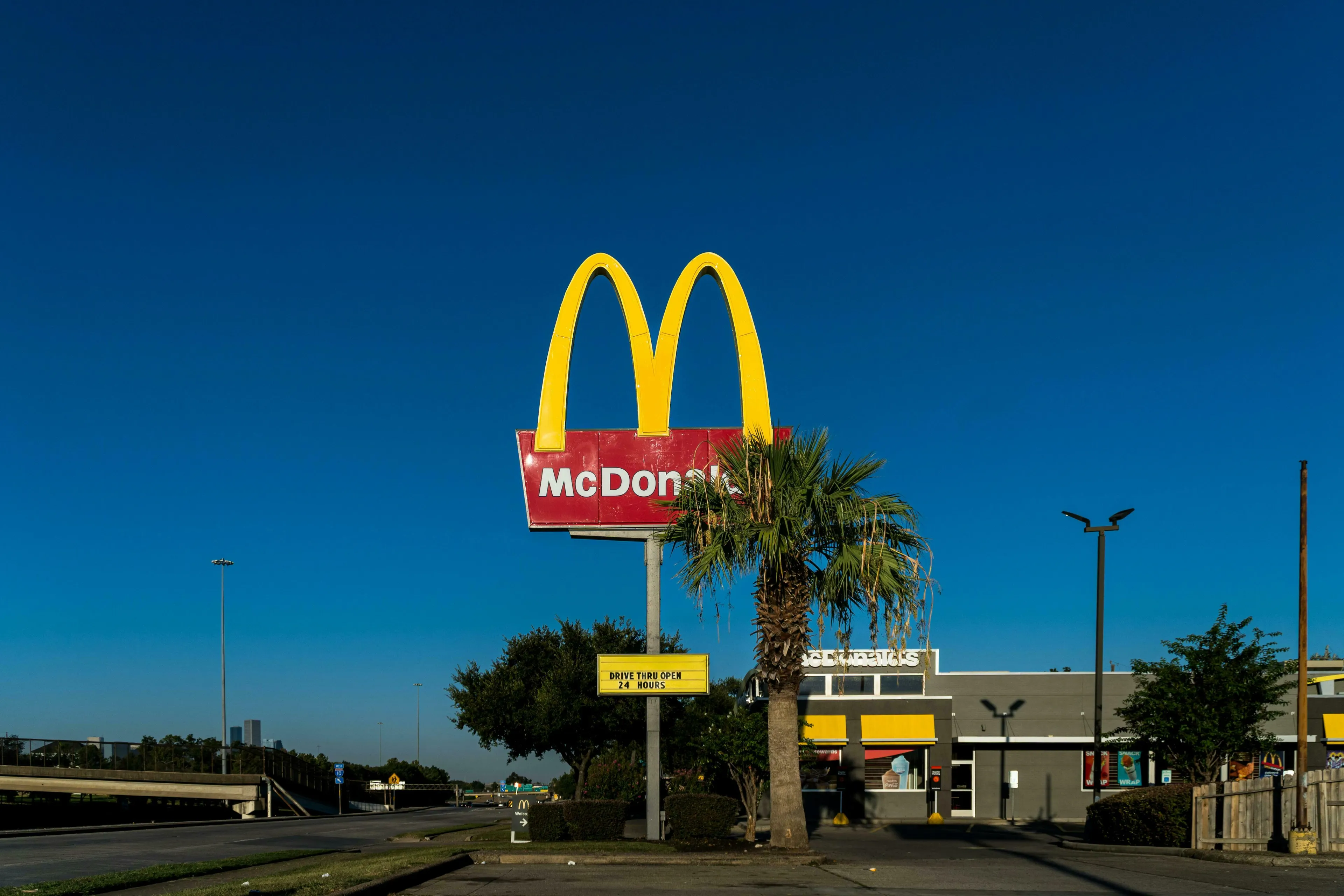 A McDonald's sign and restaurant under a clear blue sky. Reflecting on US state capitals, which one lacks a McDonald's?