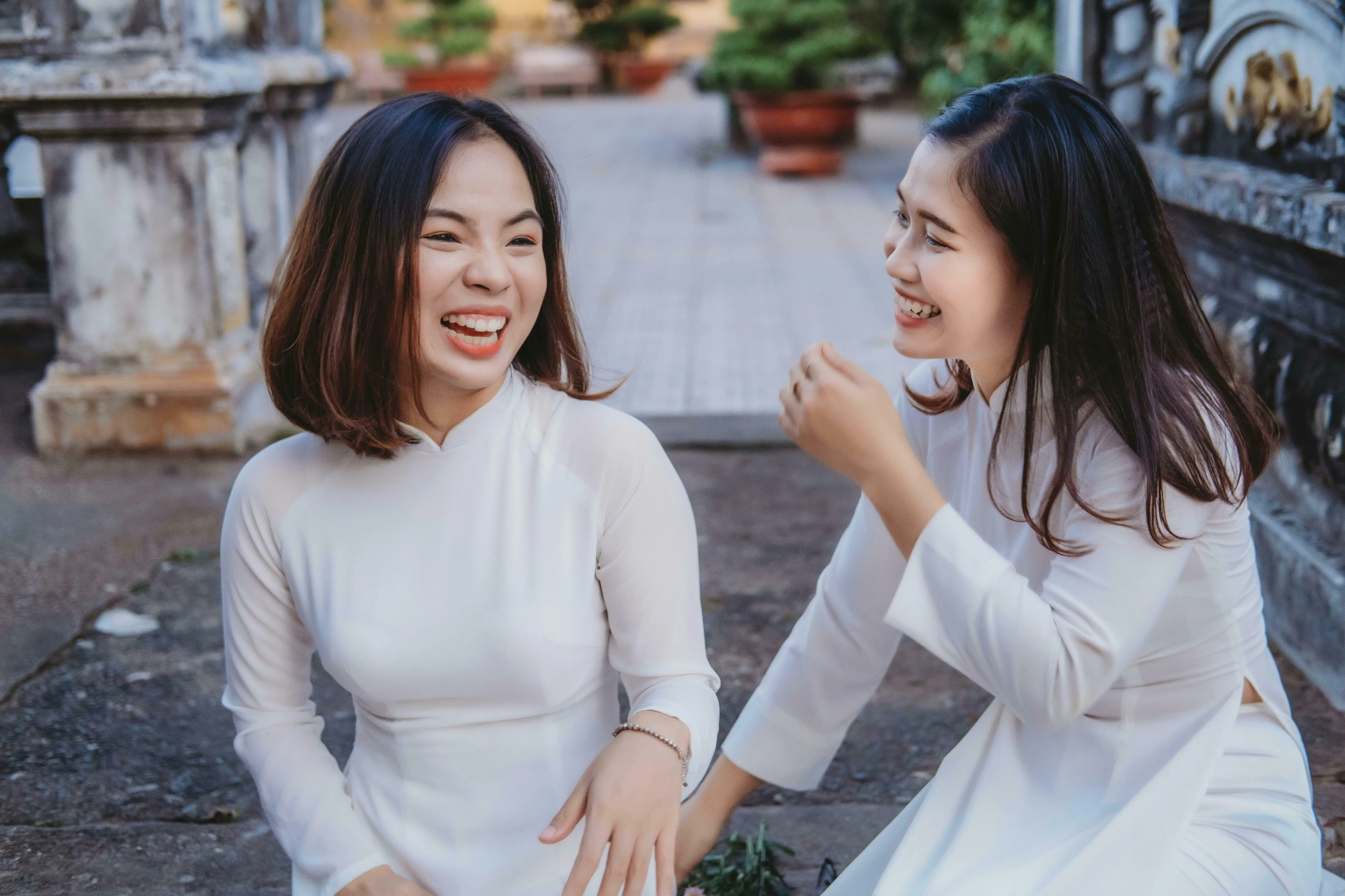 Two young women in white dresses laughing outdoors, contemplating their medieval profession and how people describe them.