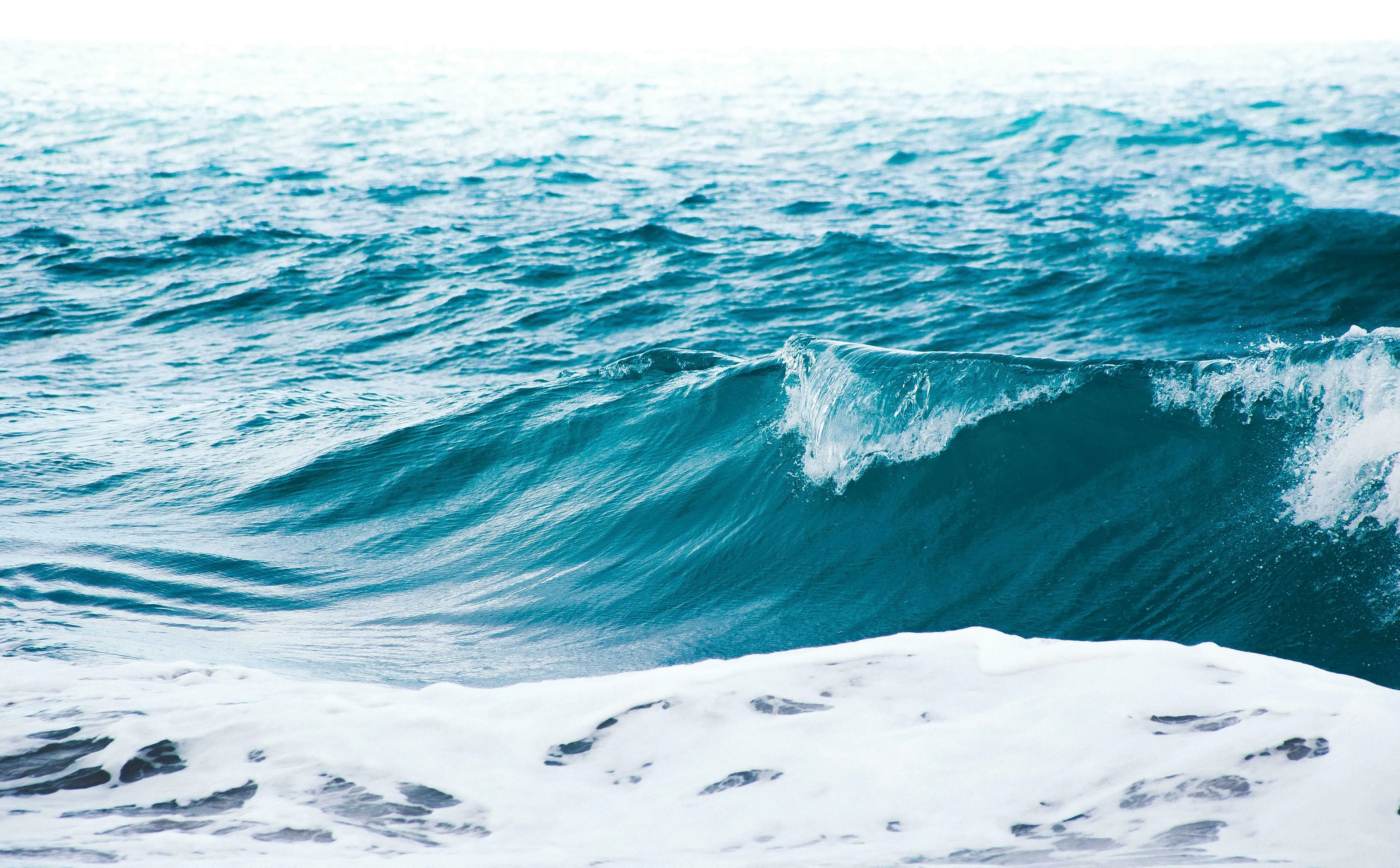 A large, powerful ocean wave with a white crest breaking near the shore, evoking the Greek god of the sea.