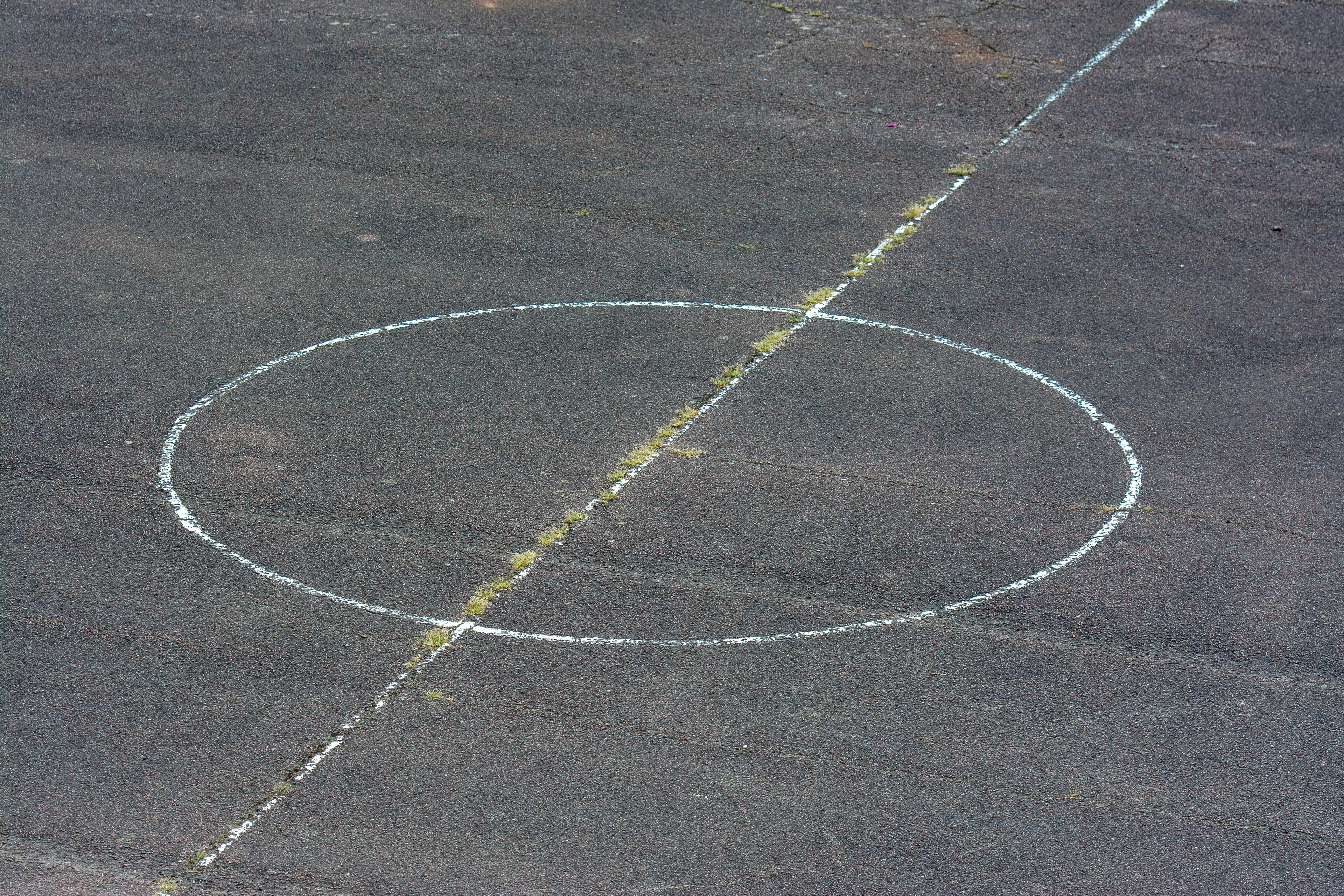 An abstract image of white lines forming a circle and a diagonal line on a gray asphalt surface. This is a general knowledge quiz.
