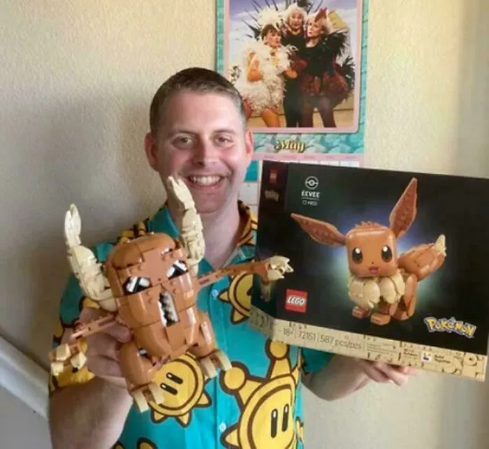 Man holding a Lego Pokemon Eevee set and a horned Lego figure smiling