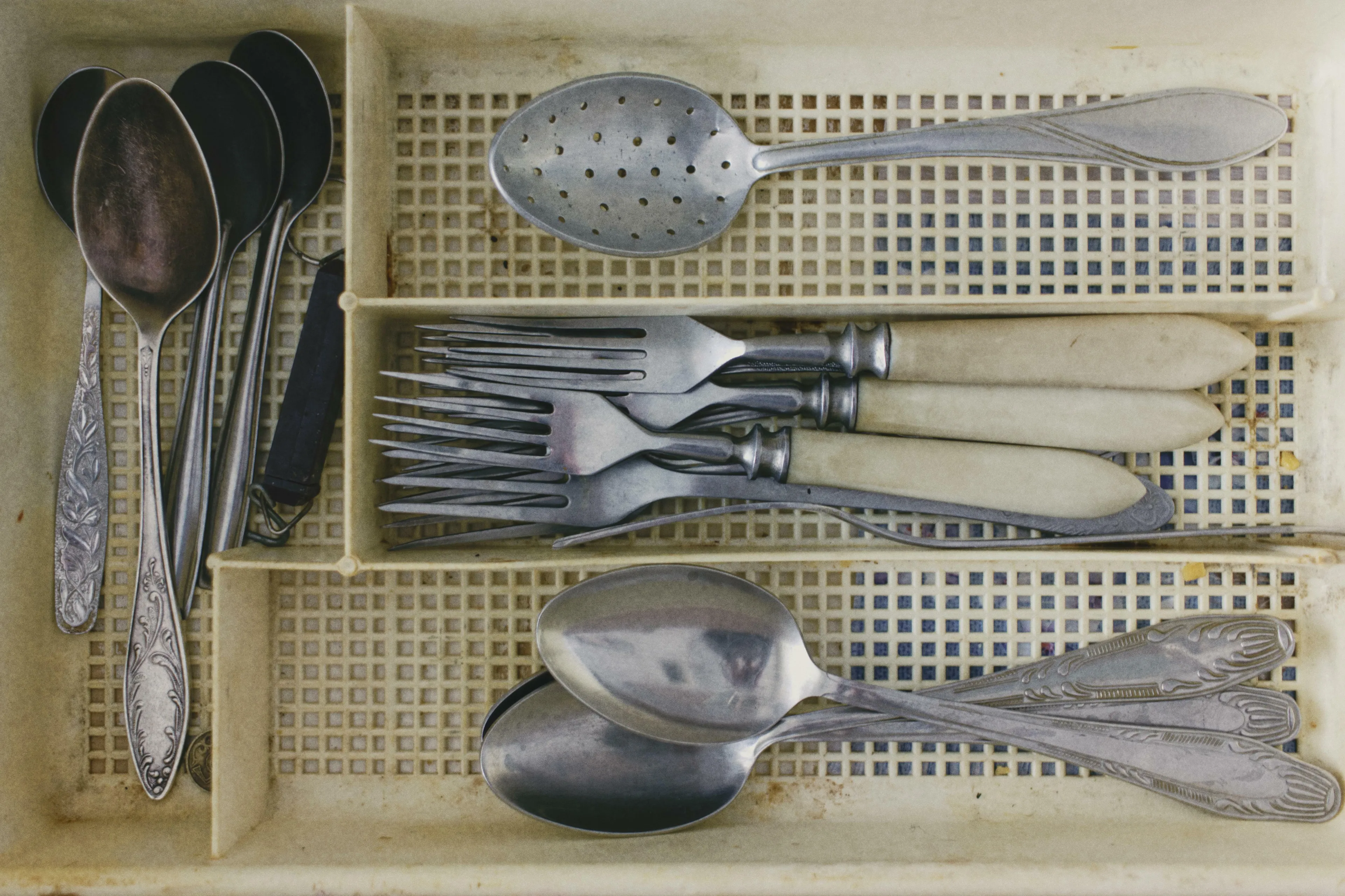 An assortment of metal cutlery, including spoons, forks, and a strainer. American vs British English words quiz.