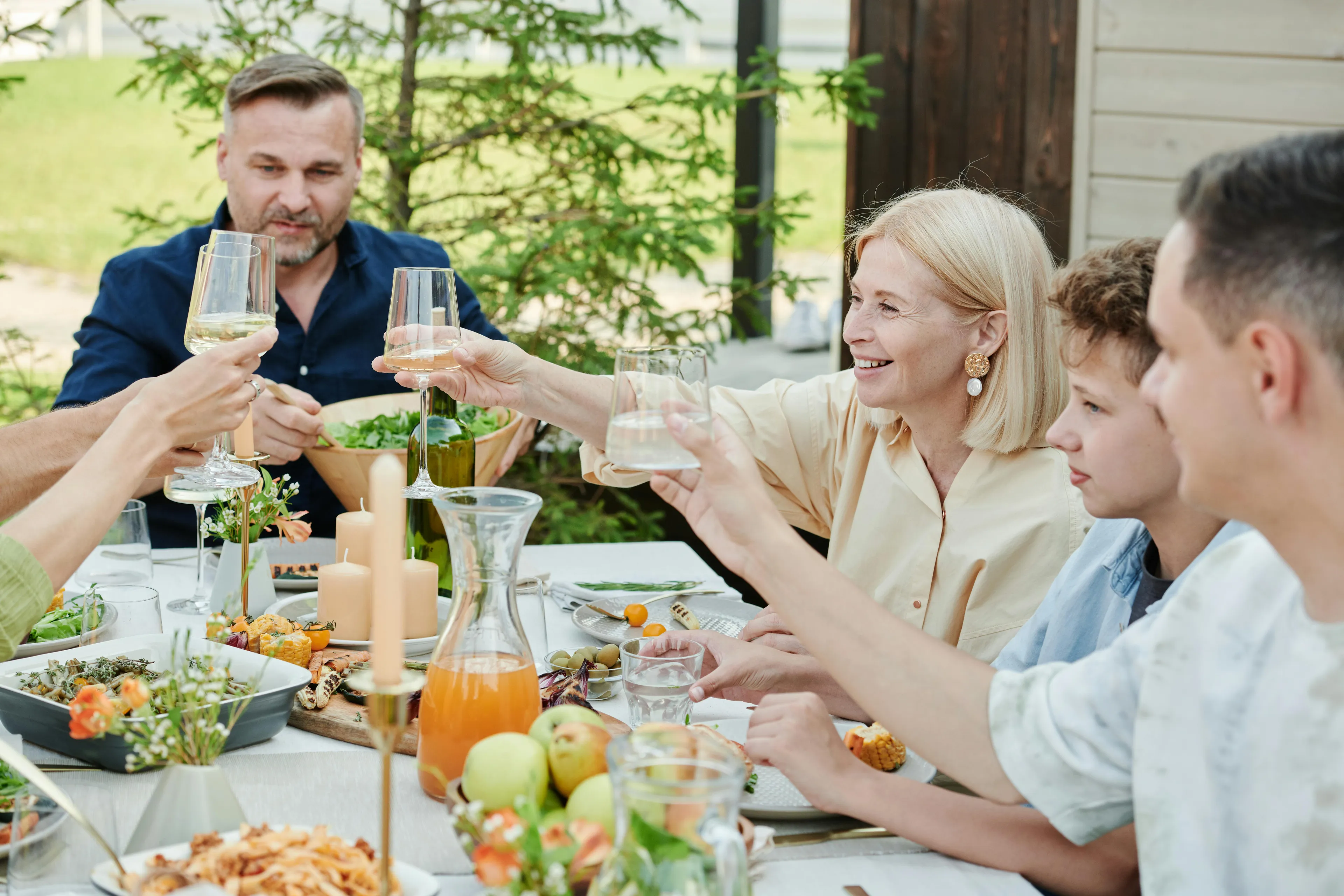 Two people toasting beers outdoors. An American would say they're having drinks in the yard, whilst a Brit would say they're in the garden. American Vs British English words quiz.
